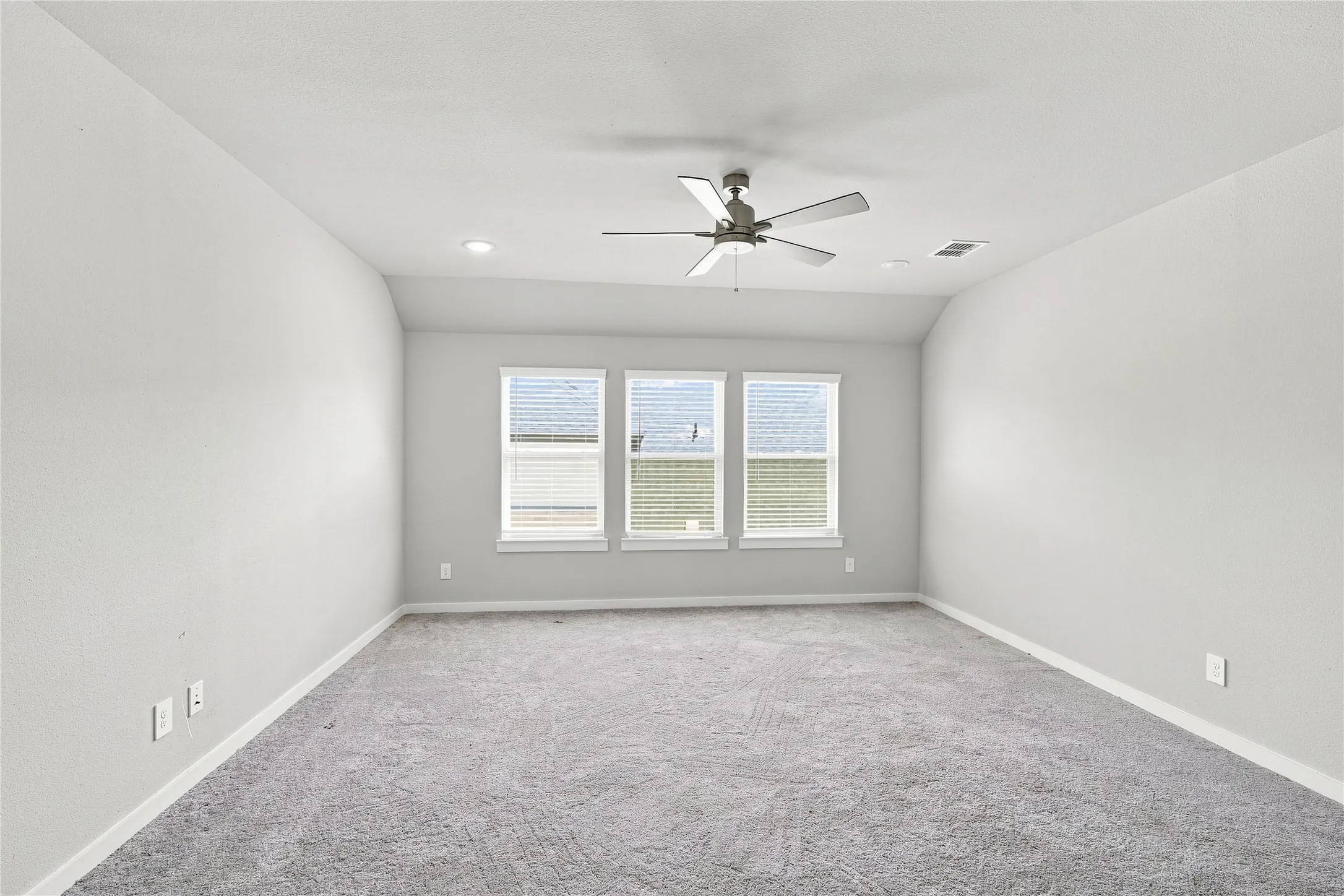 Spacious room featuring gray carpeting, a ceiling fan, recessed lighting, and three double-hung windows