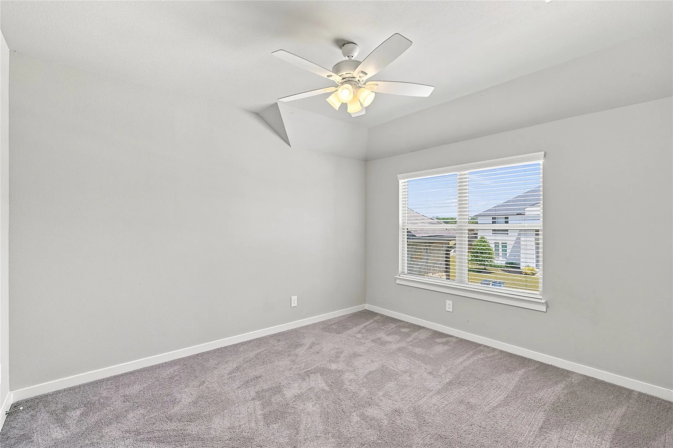 Vaulted ceiling with a ceiling fan, neutral wall color, carpeted flooring, and a large window with blinds