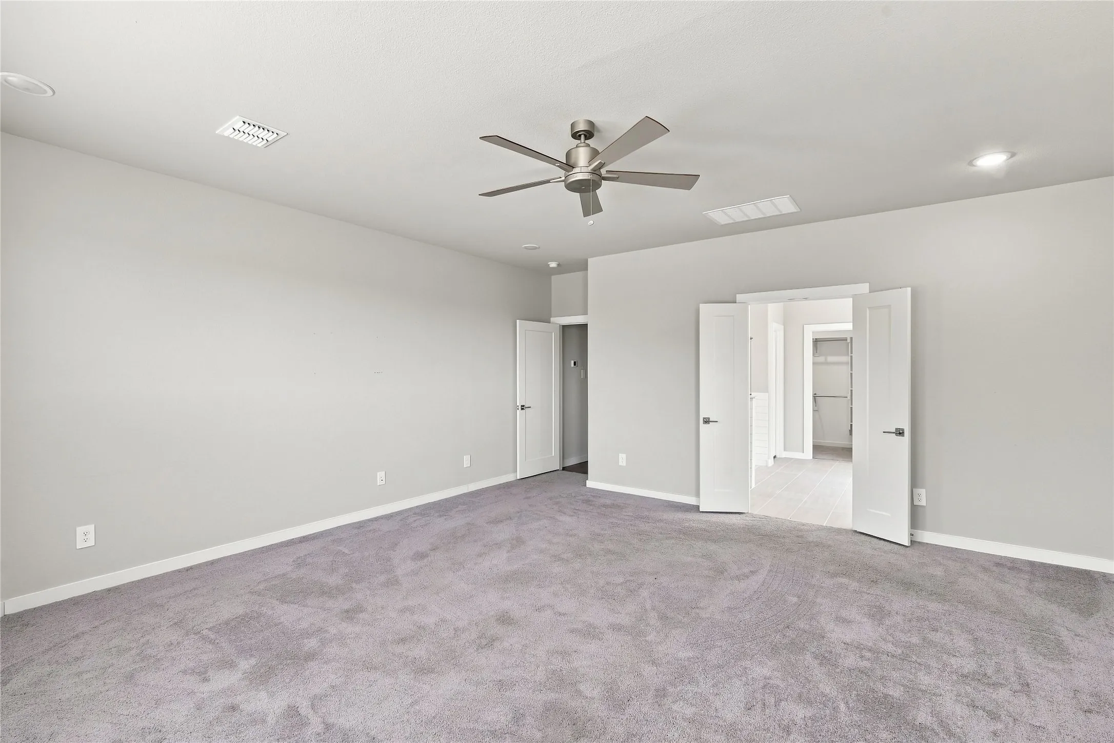 Spacious room featuring neutral carpeting, a ceiling fan, recessed lighting, and double doors