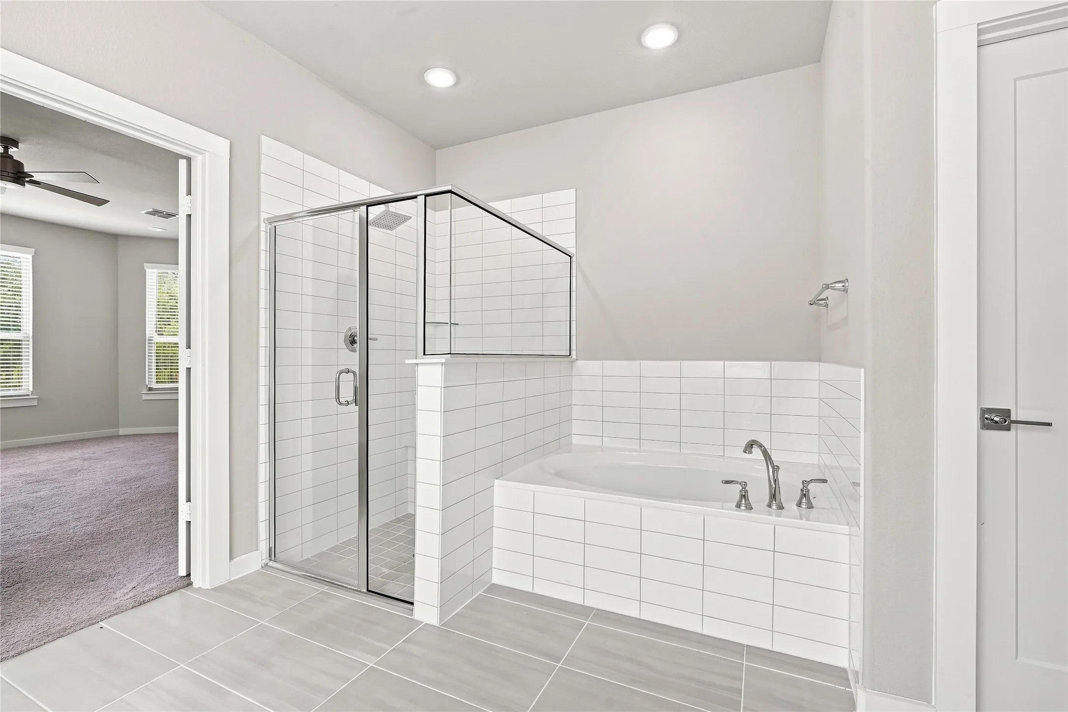 Enclosed glass shower, built-in soaking tub, subway tile surround, recessed lighting, and large format floor tiling