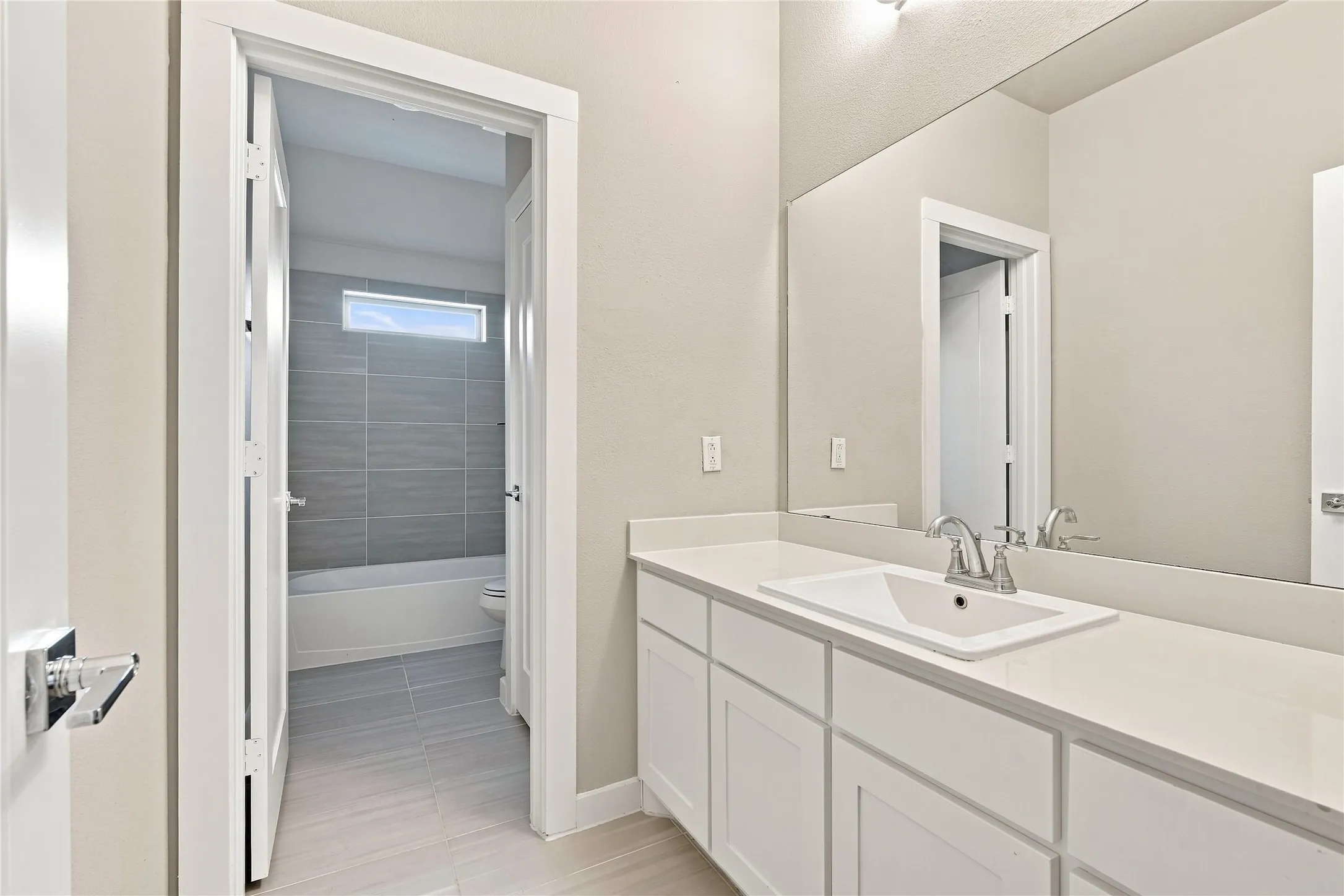White shaker-style cabinetry with a single vanity, undermount sink, and polished chrome faucet