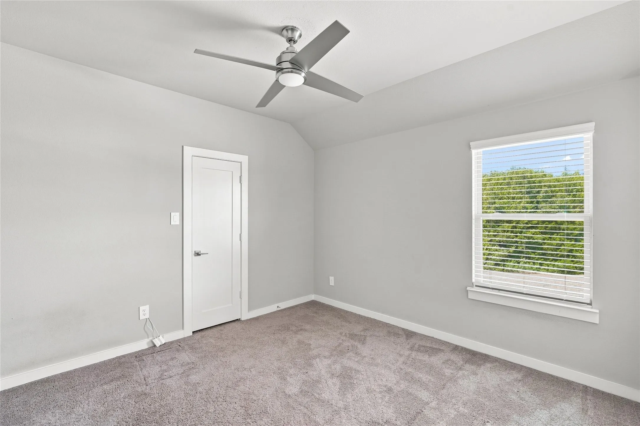 Carpeted room with a ceiling fan, a window with blinds, and a white interior door