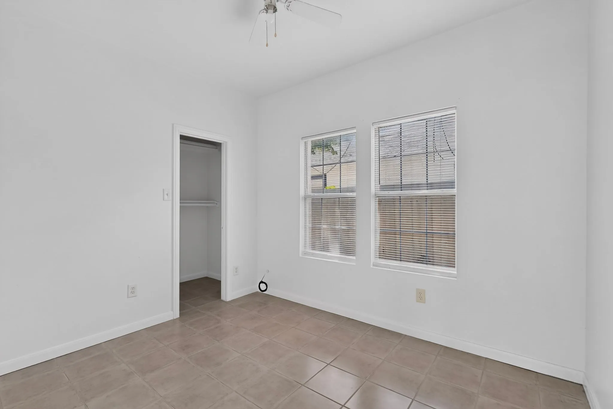 Light-toned tile flooring, white painted walls, and a ceiling fan