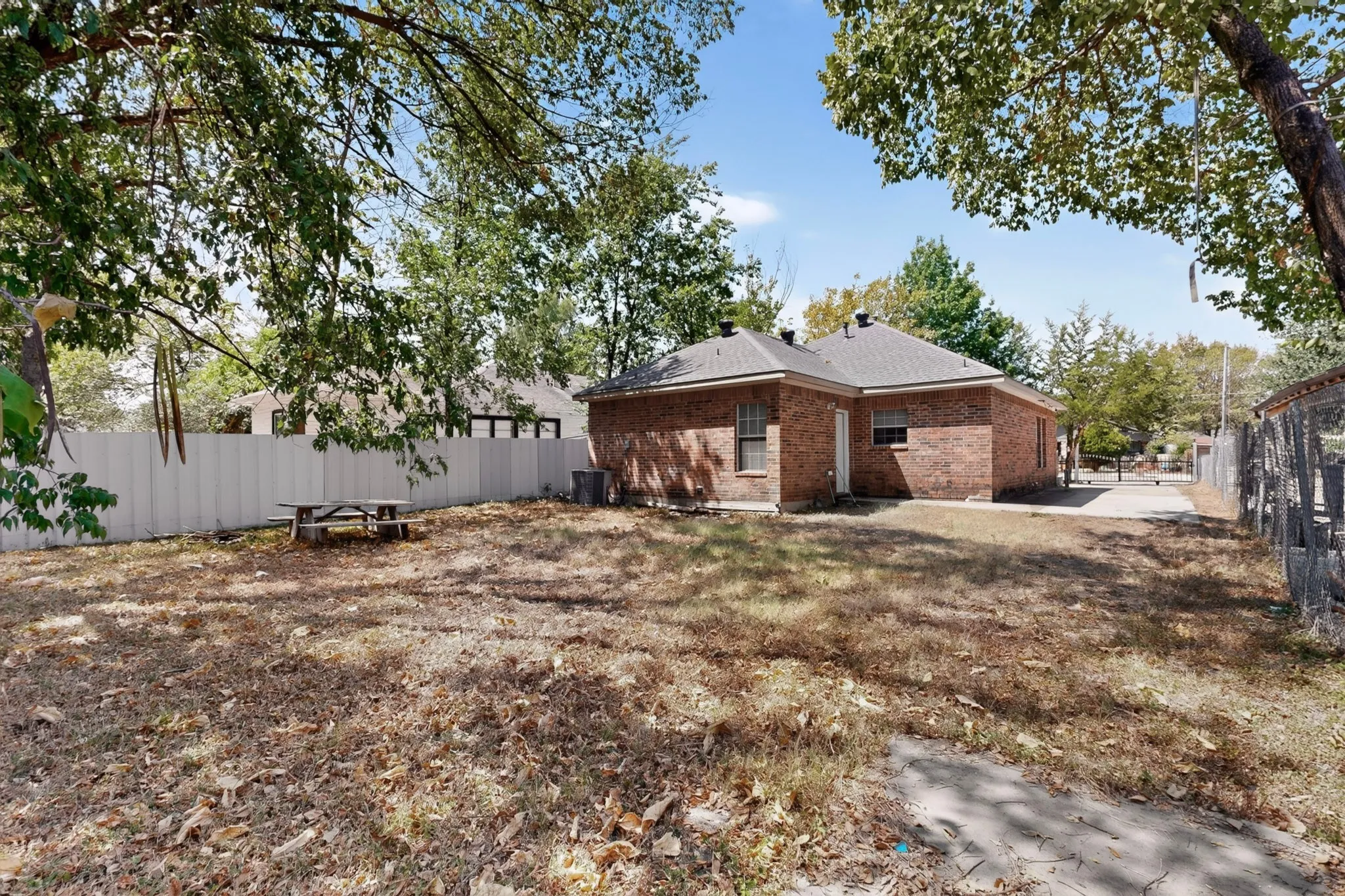 Brick exterior, shingle roof, paved driveway, privacy fence, mature trees