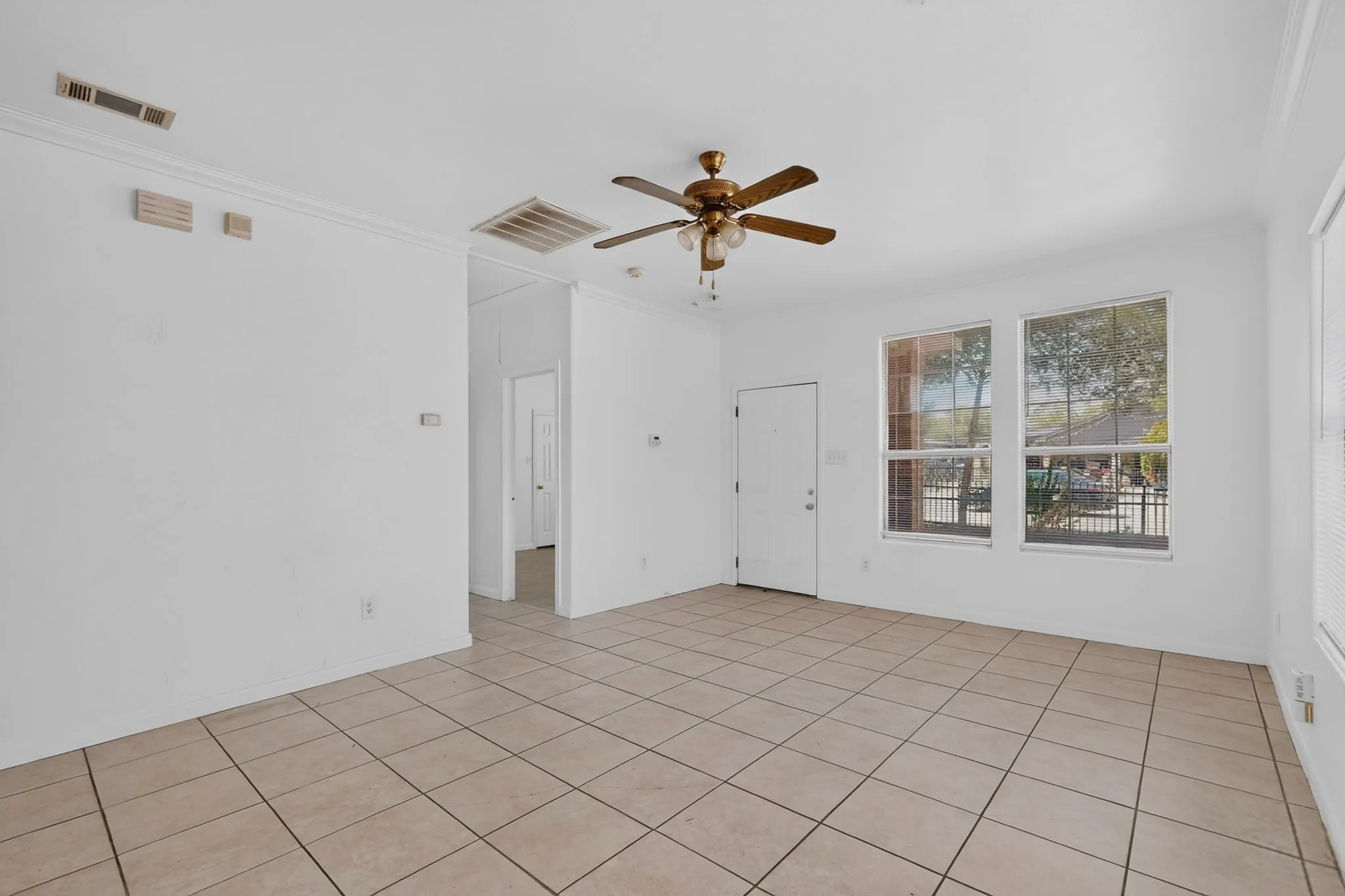 Light beige tiled flooring, white walls, and crown molding