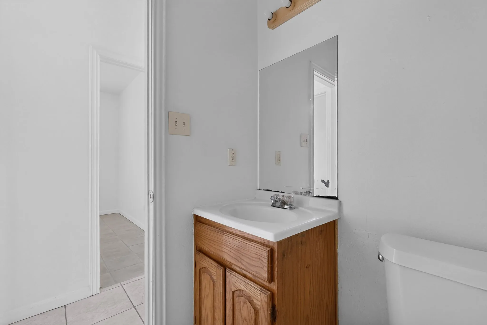 Vanity with a wood-finish base cabinet, integrated sink, and wall-mounted mirror