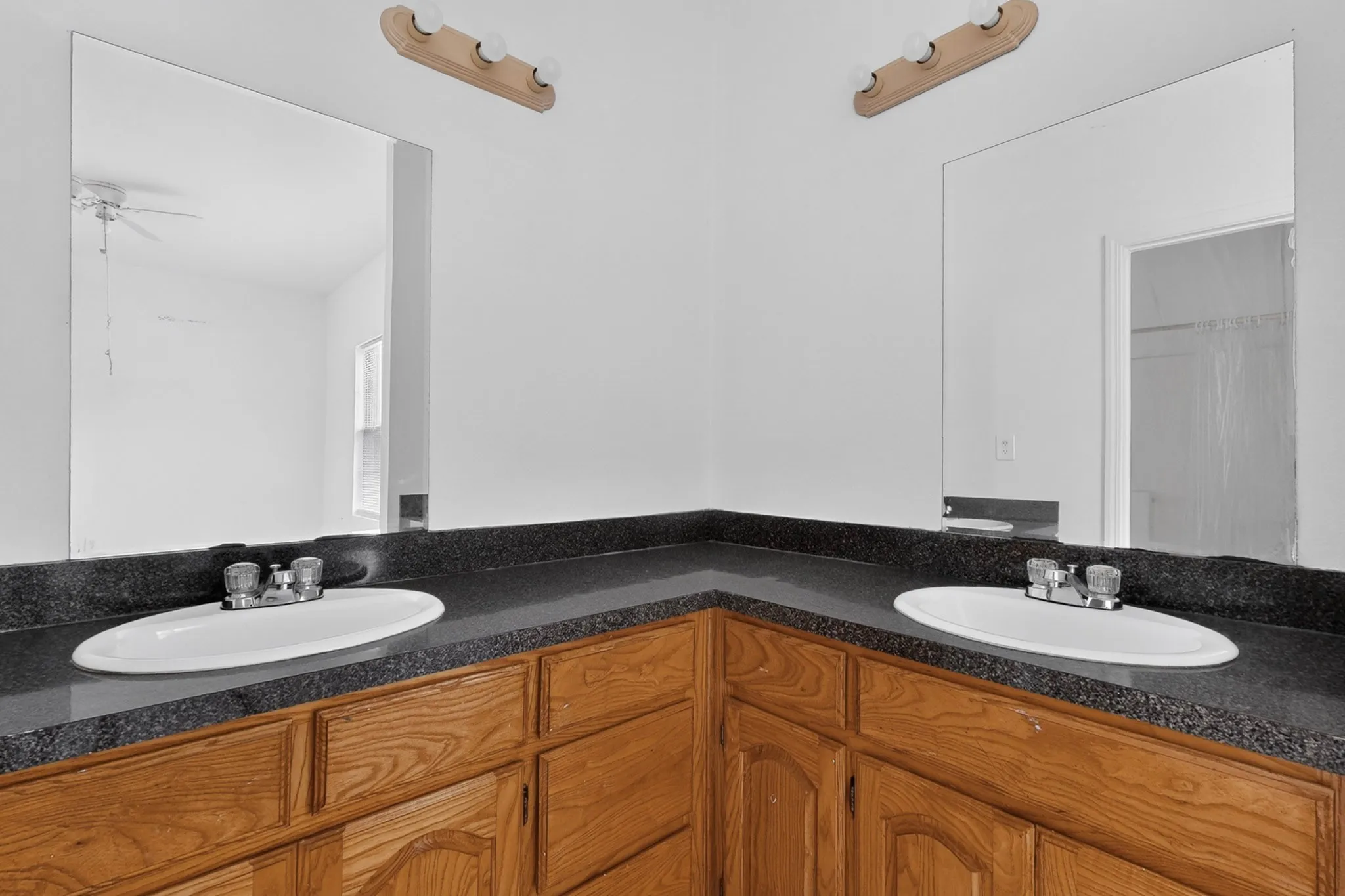 Dual oval undermount sinks with two-handle chrome faucets set in a dark speckled countertop