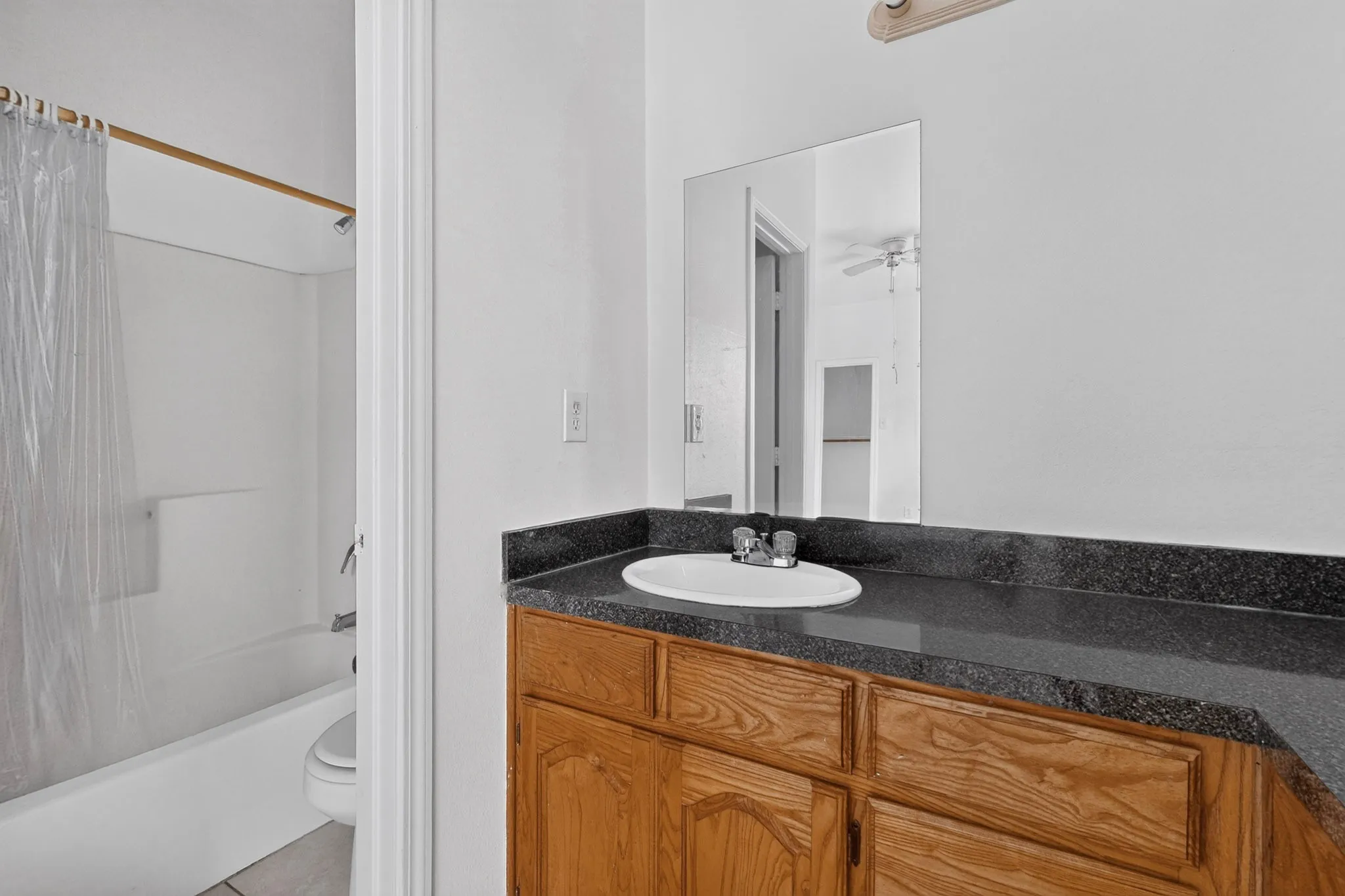 Wood-finish vanity with a dark countertop and integrated sink