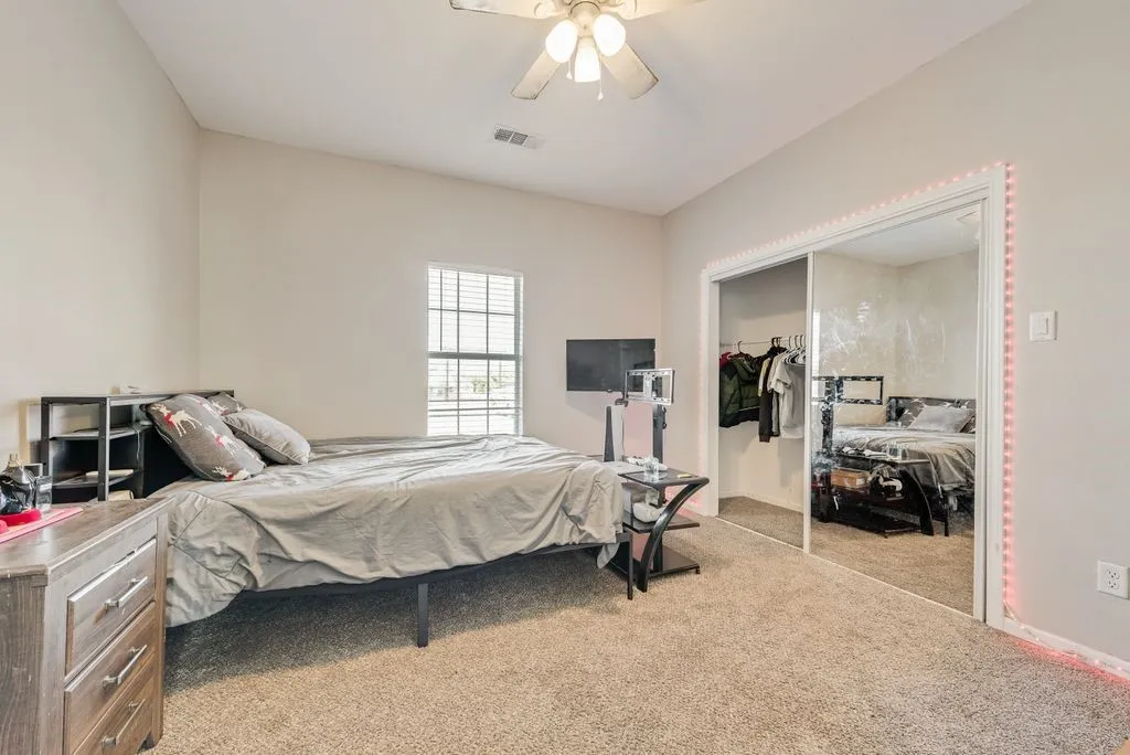 Carpeted room with a ceiling fan, a window with blinds, and a mirrored sliding closet door