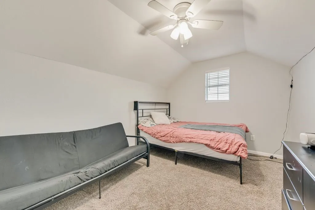 Vaulted ceiling with a ceiling fan, carpeted flooring, and a window with blinds