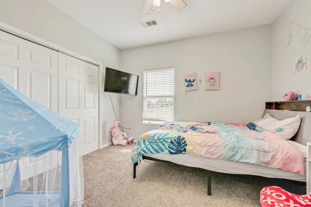 Light gray wall paint, textured carpet flooring, white bi-fold closet doors, and a ceiling fan with integrated lighting