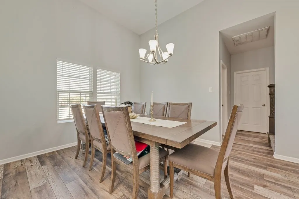 Vaulted ceilings, wood-finish flooring, and multiple windows with blinds