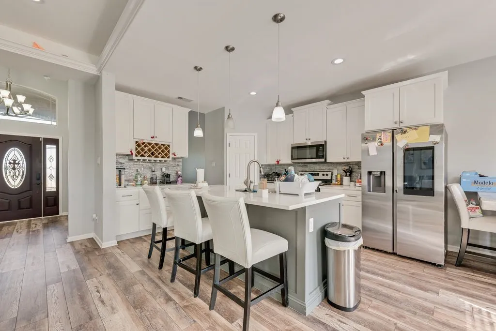 Kitchen featuring white cabinetry, a central island with countertop seating, wood-finish flooring, and a decorative tile backsplash