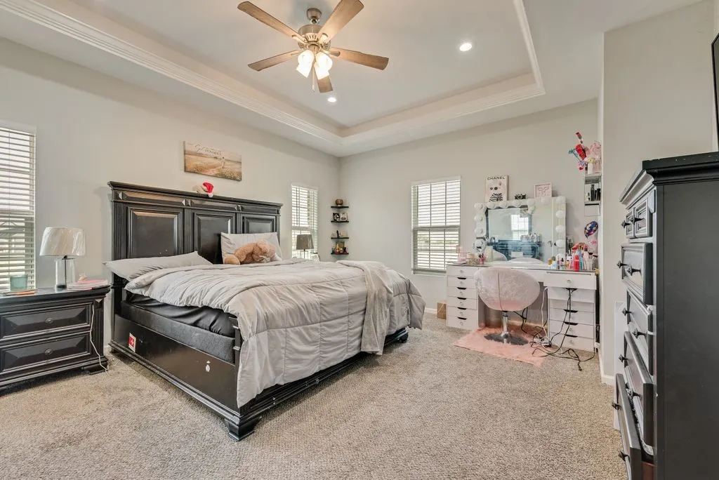 Tray ceiling with recessed lighting, ceiling fan, carpeting, and multiple windows with blinds