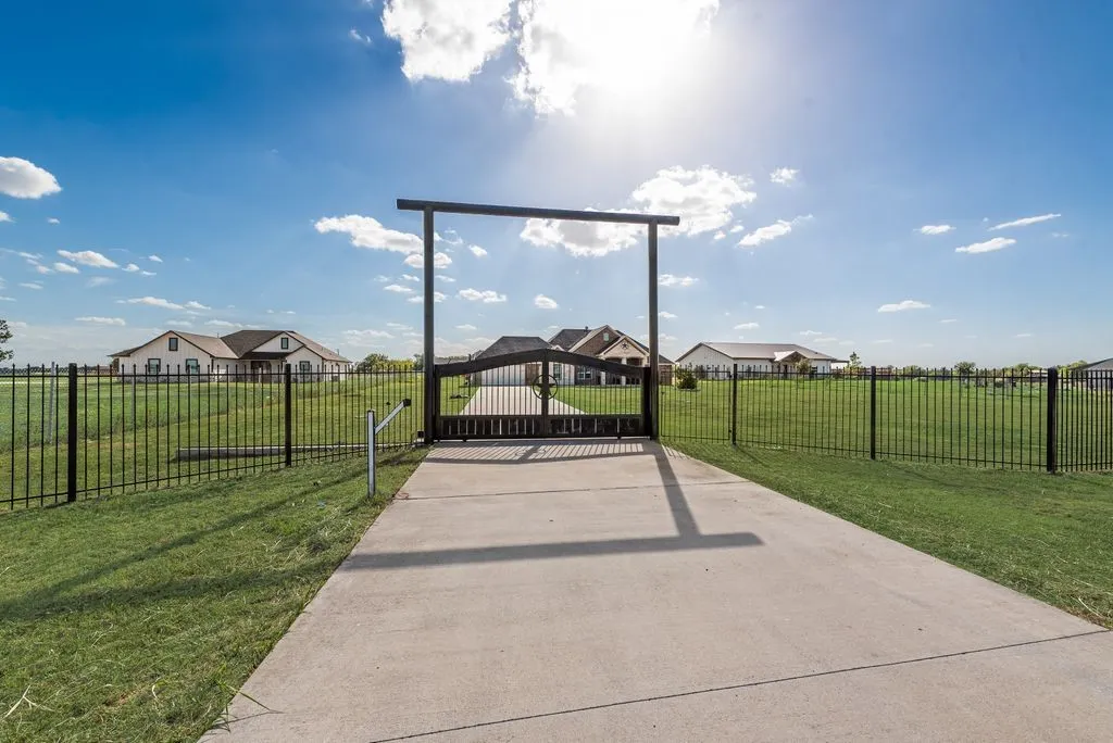Gated entrance with a concrete drive and black metal fencing