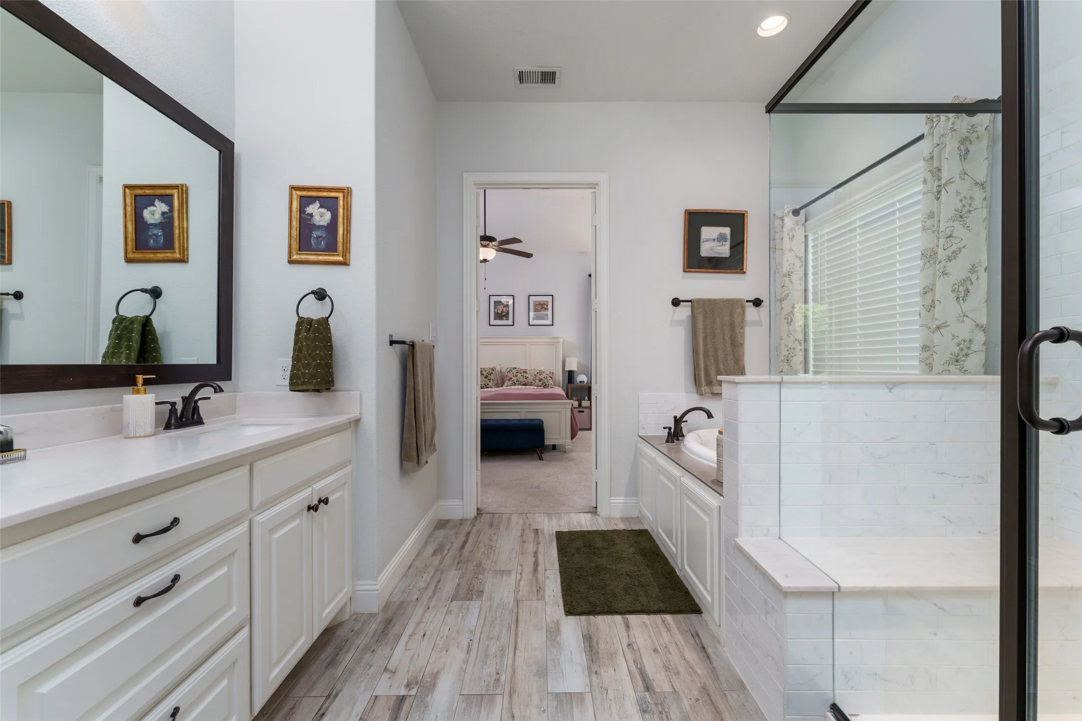 Large and beautiful primary bathroom with white cabinets and two vanities.
