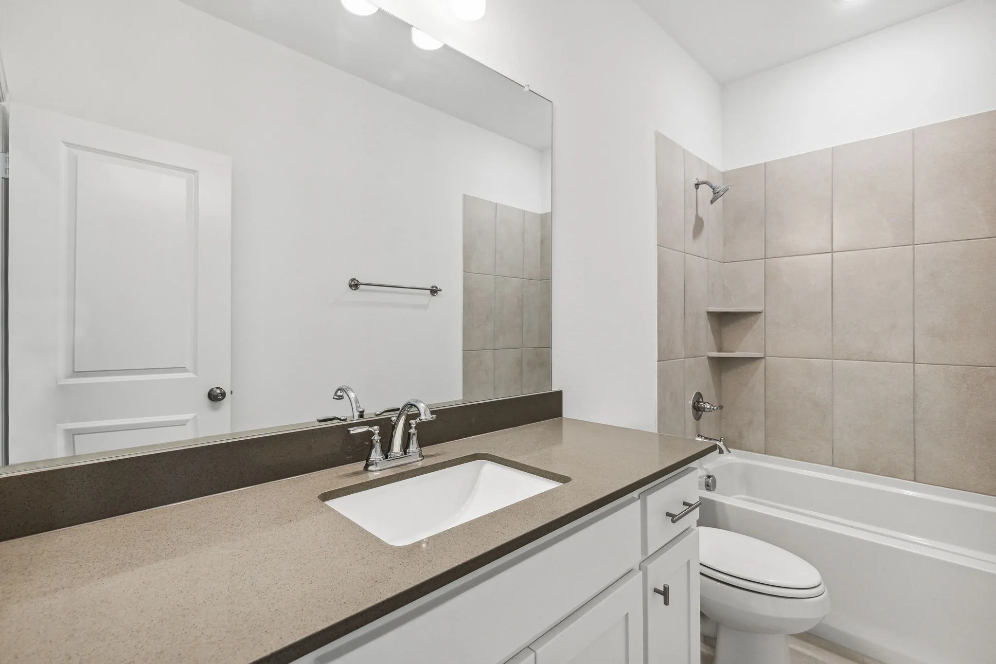 Secondary Bathroom Features Quartz Countertops and a Bathtub with Oversized Tile