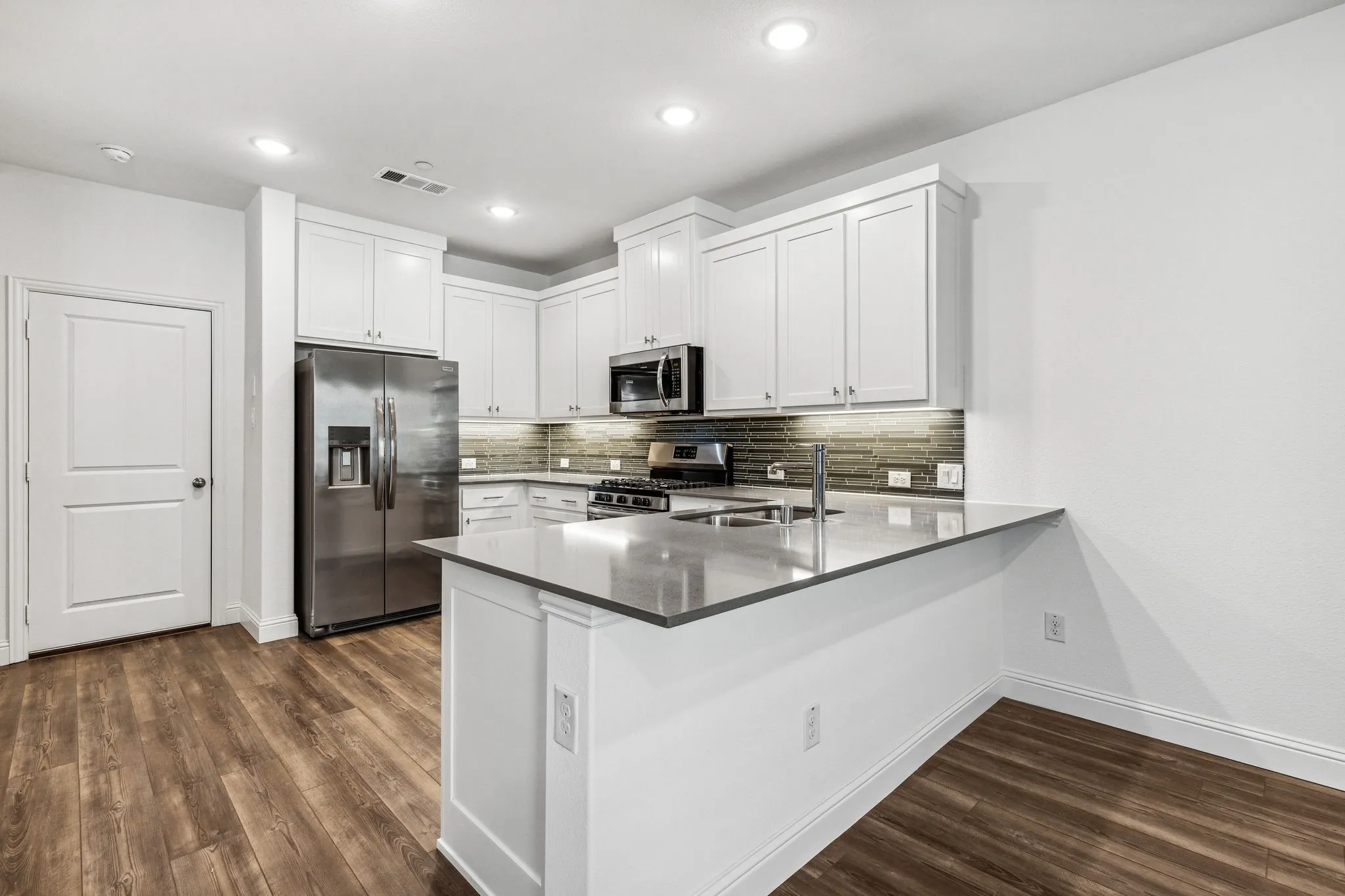 Kitchen Boasts Quartz Countertops, Tile Backsplash, and Shaker Cabinets