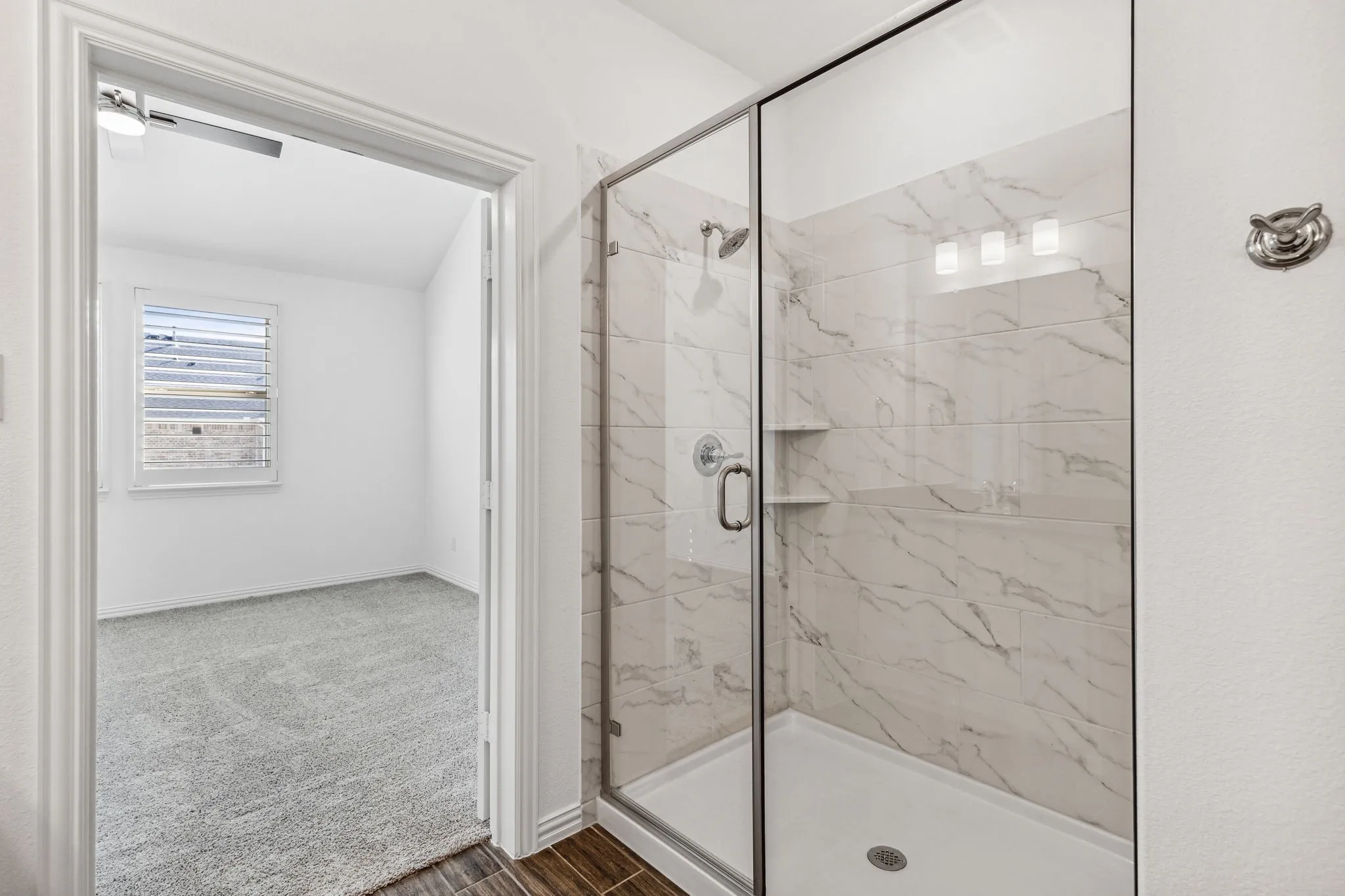Primary En-suite Bath Features a Walk-in Shower with Marble-look Tile Shower Surround