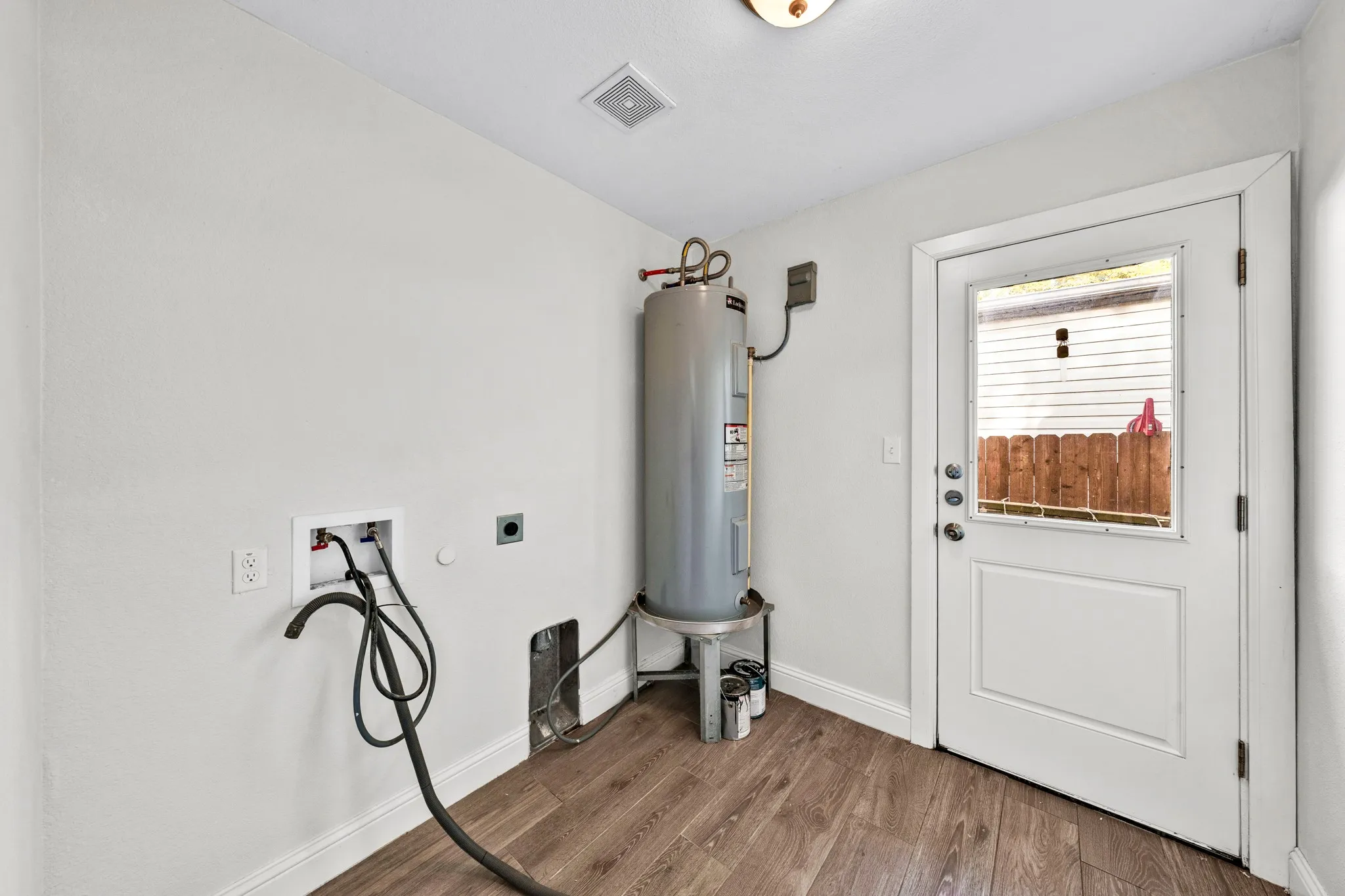 Utility area featuring wood-finish flooring, white painted walls, and a water heater