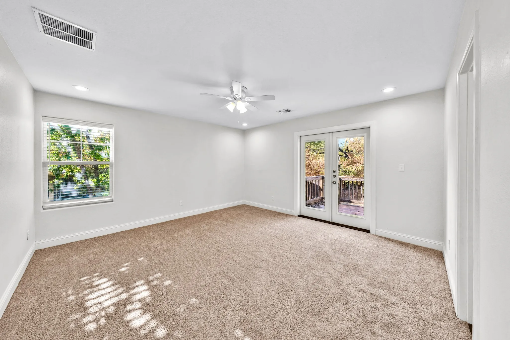 Expansive room featuring light-colored carpeting, white walls, recessed lighting, and a ceiling fan