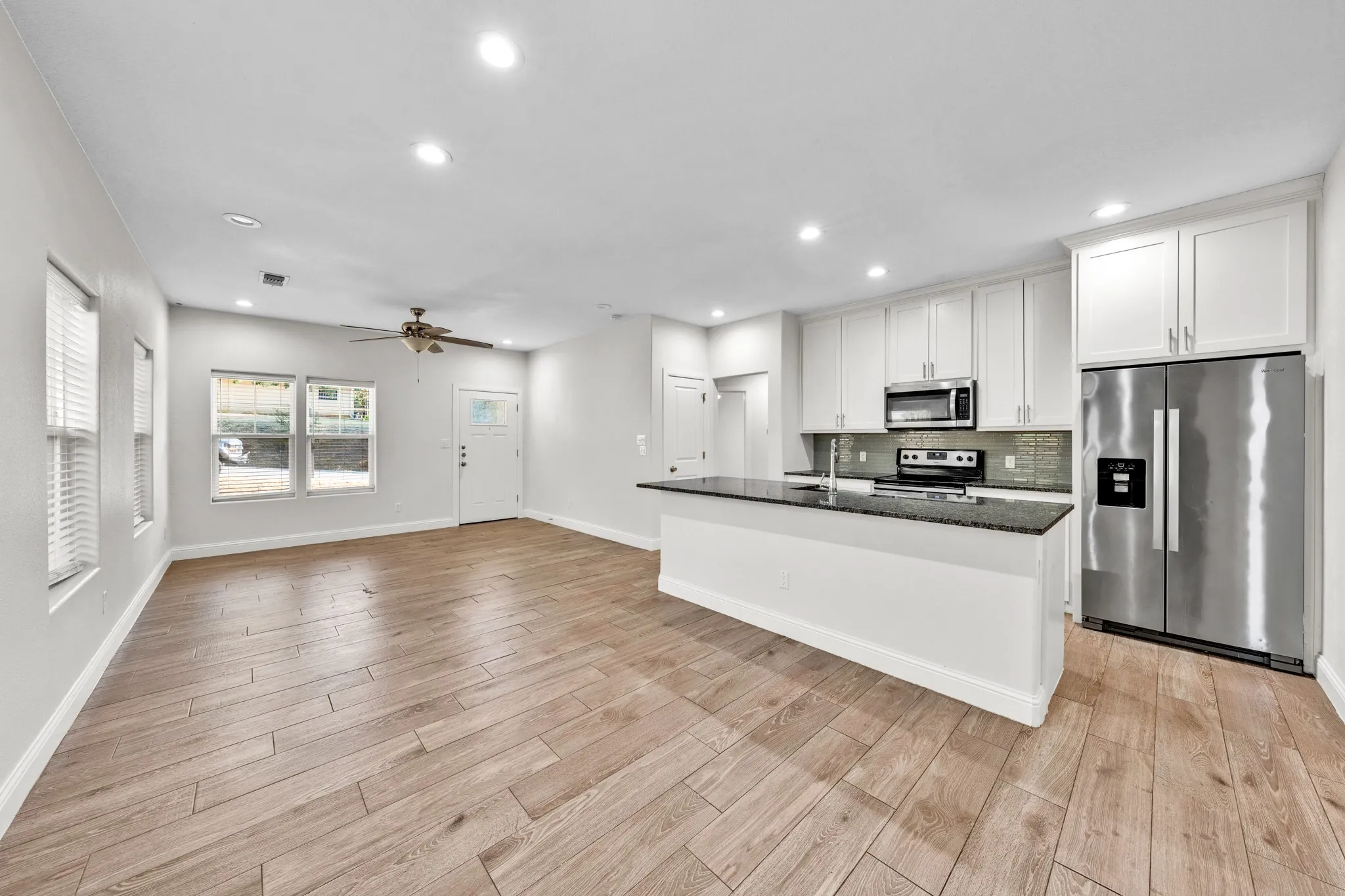Open-concept living area featuring wood-finish flooring, recessed lighting, and a ceiling fan