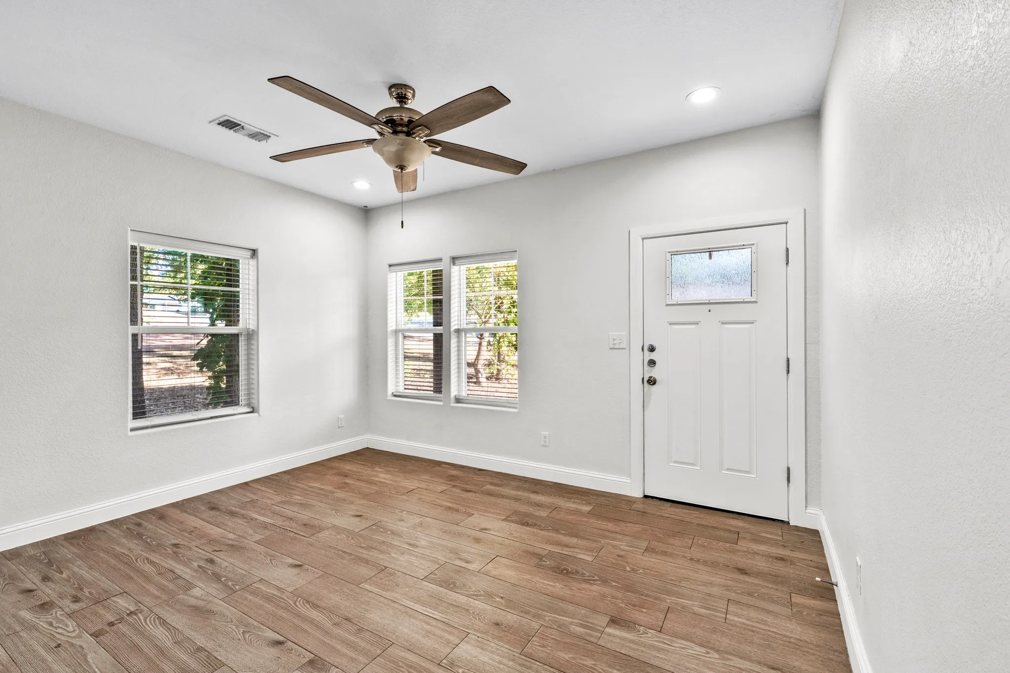 Wood-finish flooring, multiple windows with blinds, recessed lighting, and a ceiling fan