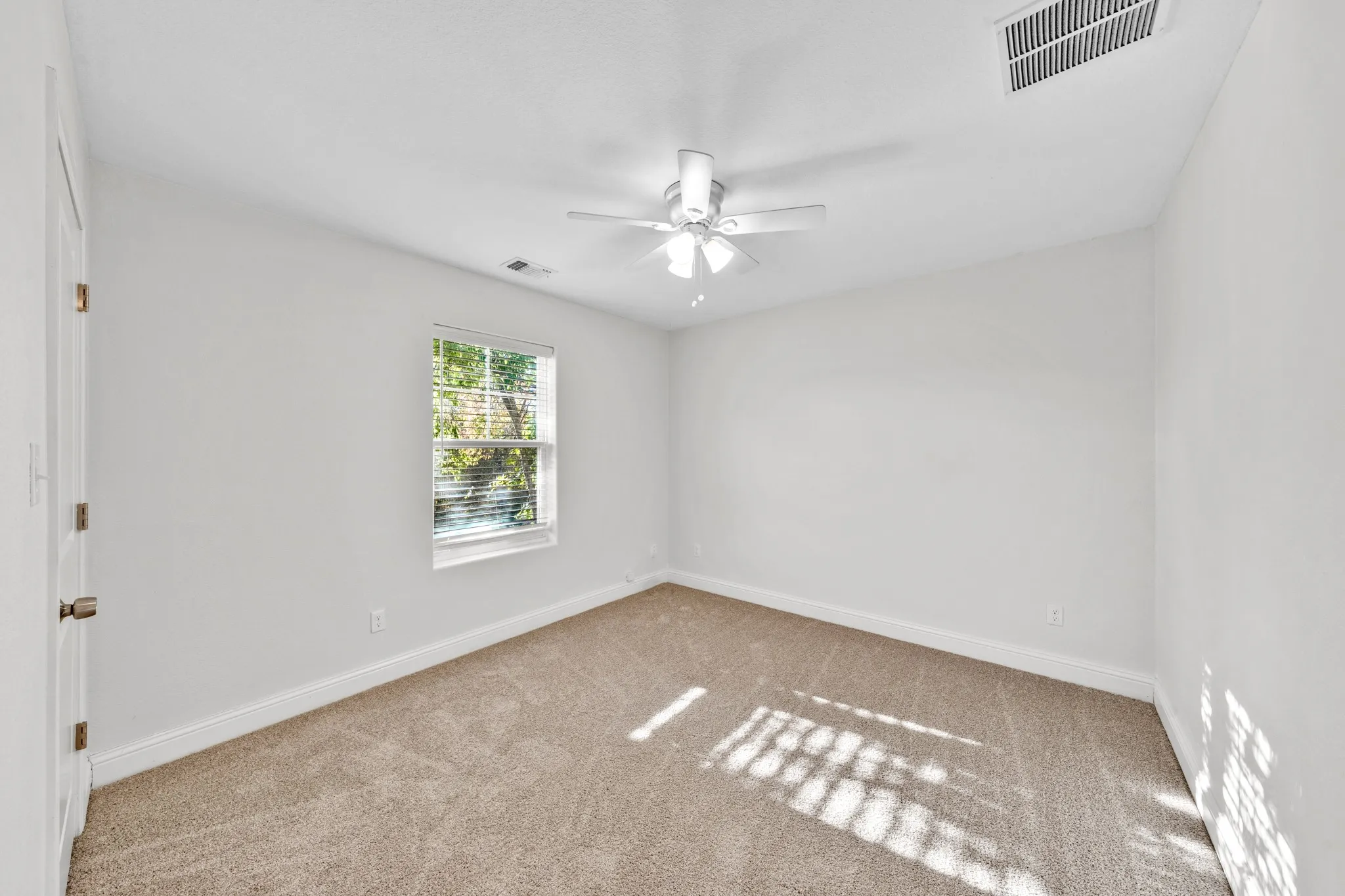 Neutral wall paint, carpeted flooring, window with blinds, ceiling fan with light fixture, and white trim