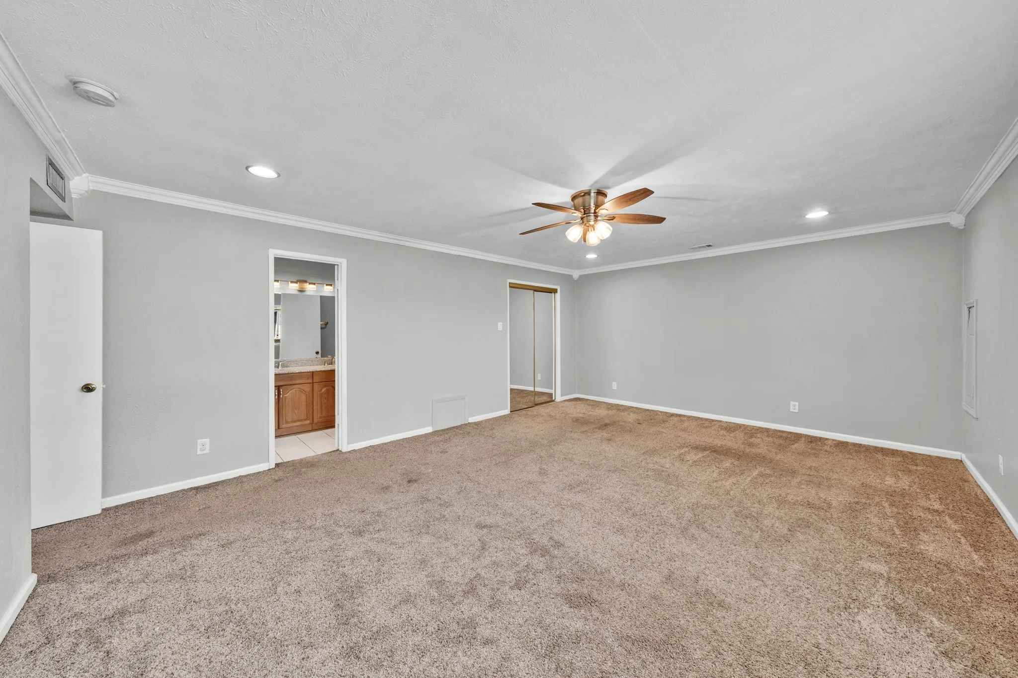 Spacious room featuring carpeting, crown molding, a ceiling fan, recessed lighting, and mirrored closet doors