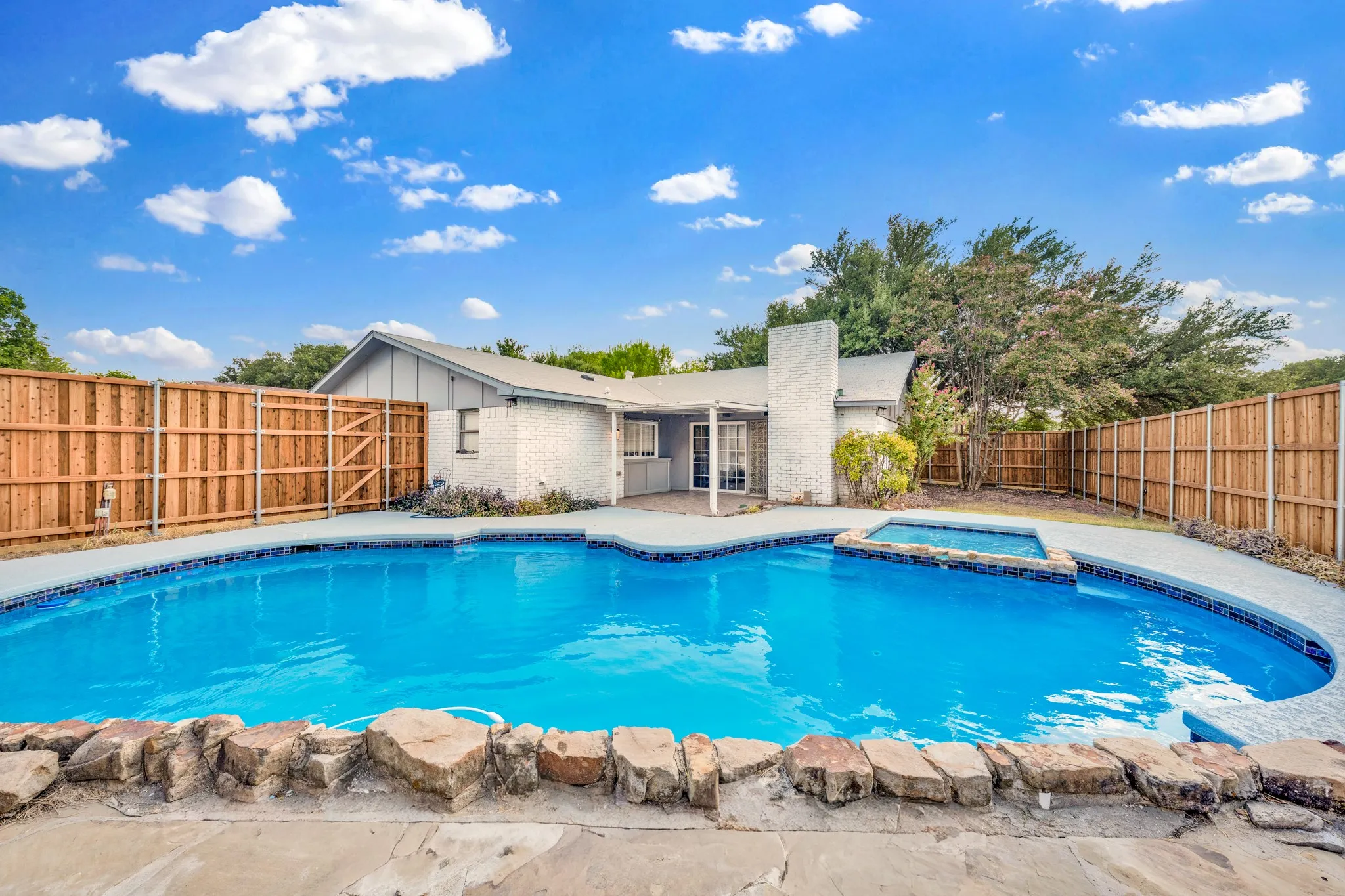 Exterior featuring a fenced backyard, swimming pool, and raised spa
