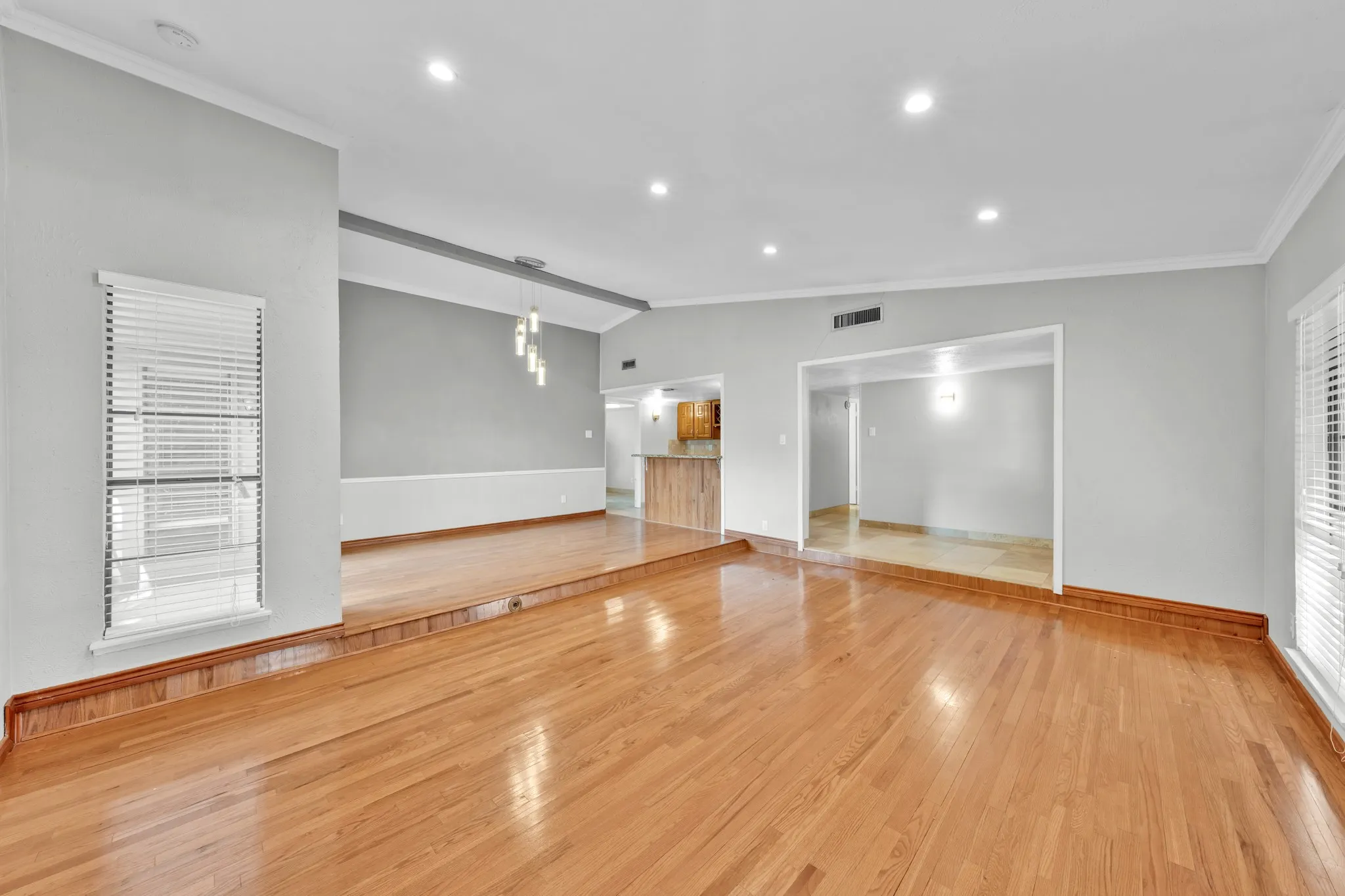 Hardwood flooring throughout, recessed ceiling lighting, light-toned walls, decorative ceiling light fixture, and arched doorway