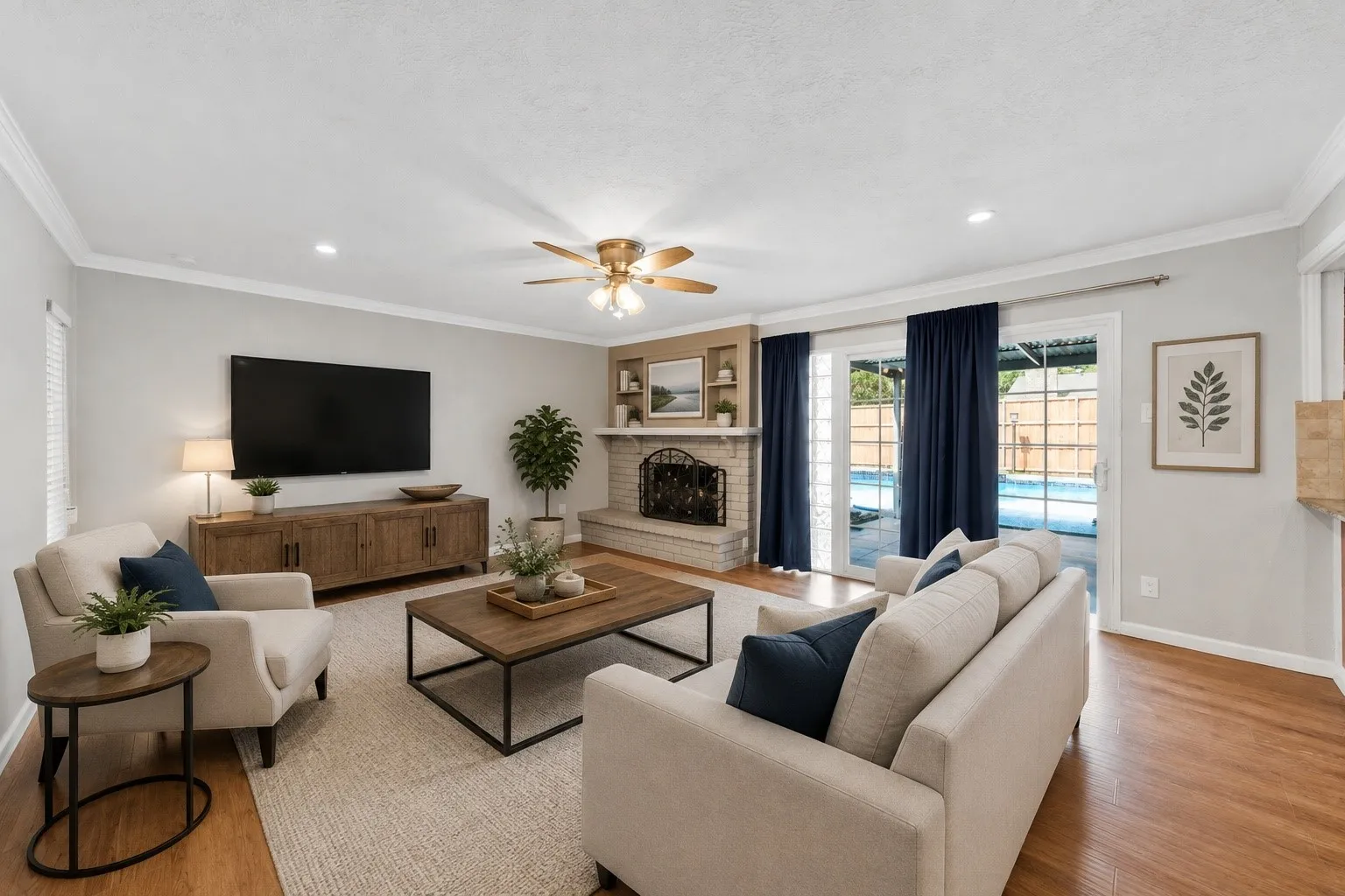 Hardwood flooring, crown molding, brick fireplace with mantel, ceiling fan, and sliding glass doors with direct outdoor access