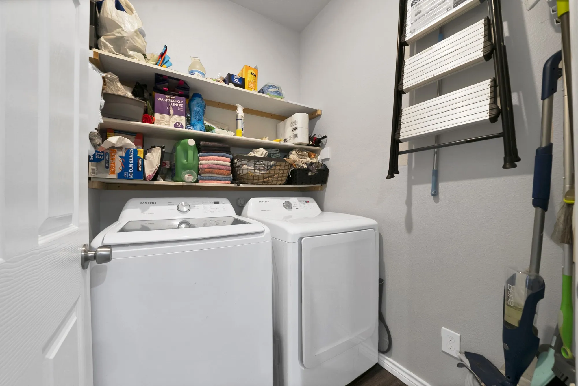 Laundry area featuring built-in shelving and wood-finish flooring