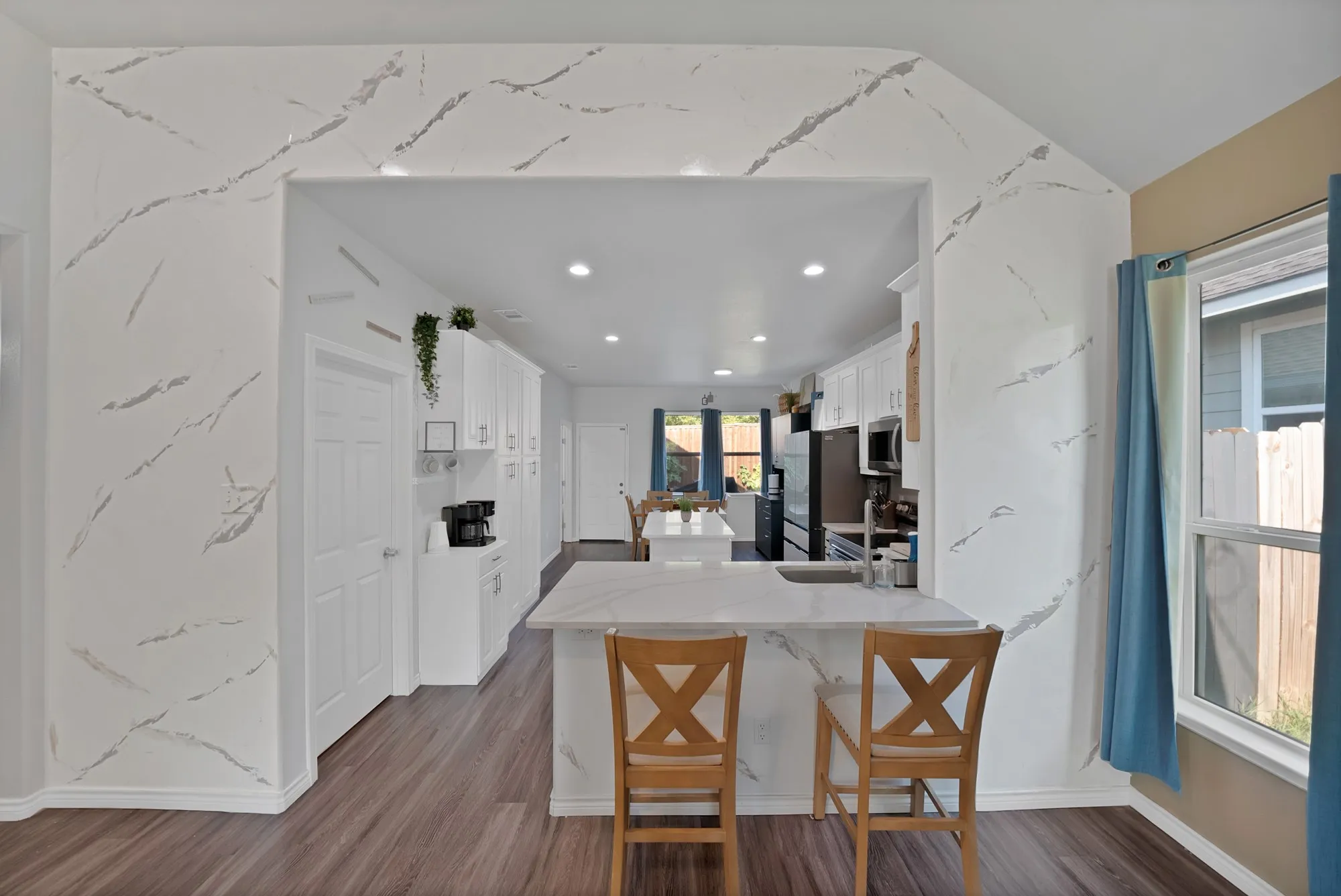 Kitchen featuring a peninsula with integrated sink, recessed lighting, white cabinetry, and wood-finish flooring