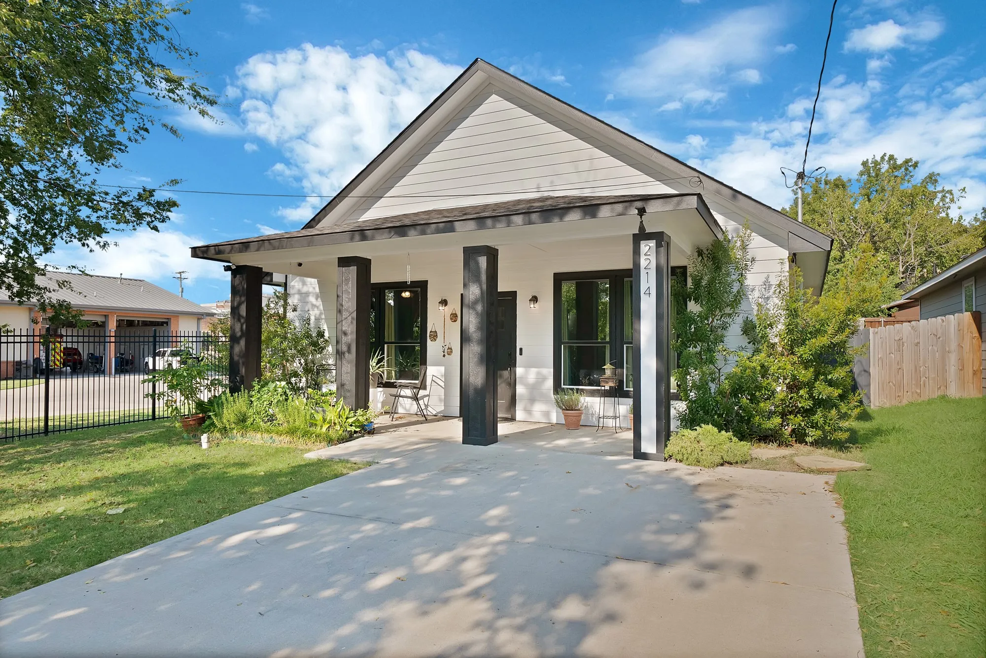 Modern façade with white siding, dark trim, and a covered porch with substantial support columns