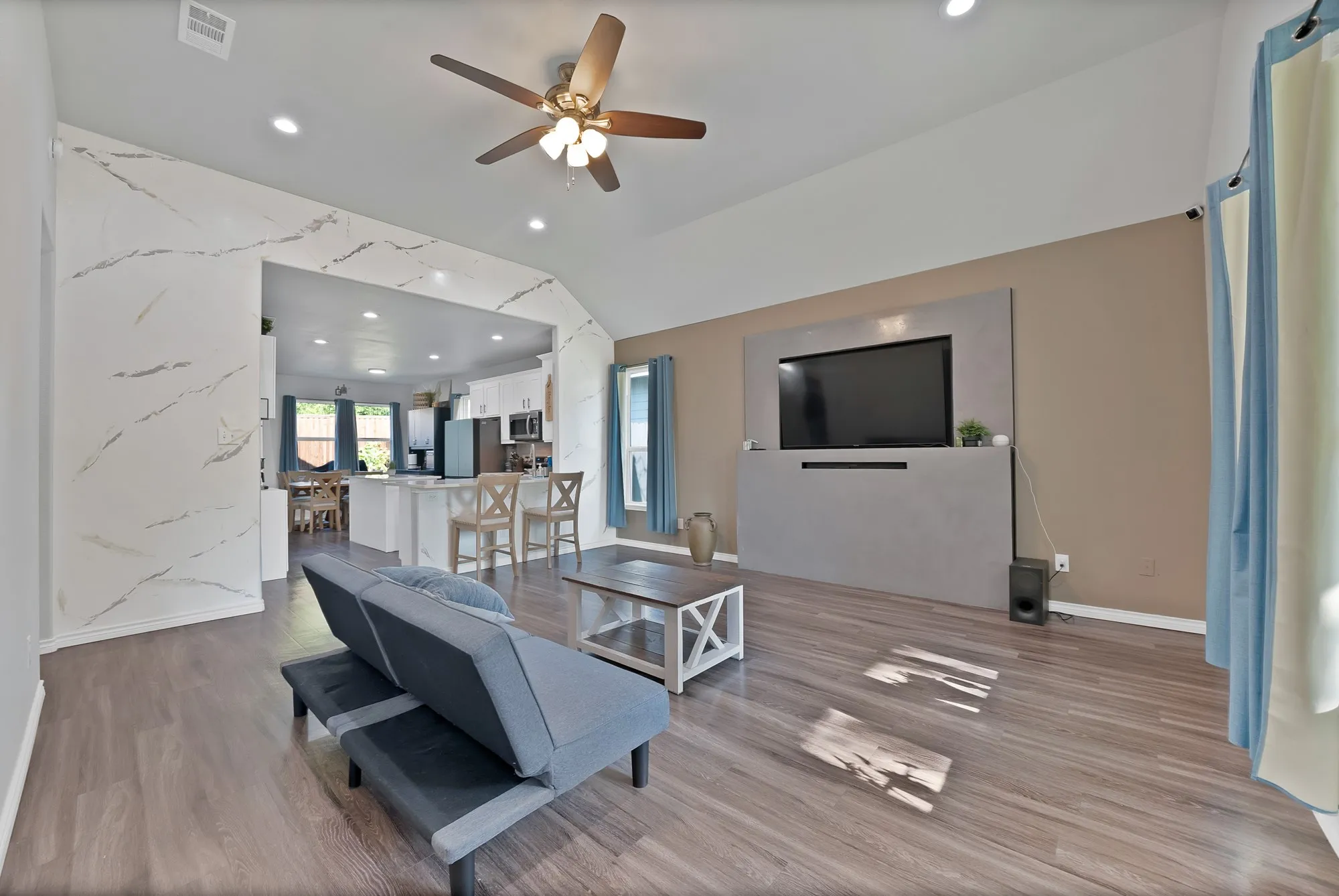 Vaulted ceiling, recessed lighting, wood-finish flooring, built-in entertainment center, and open-concept layout