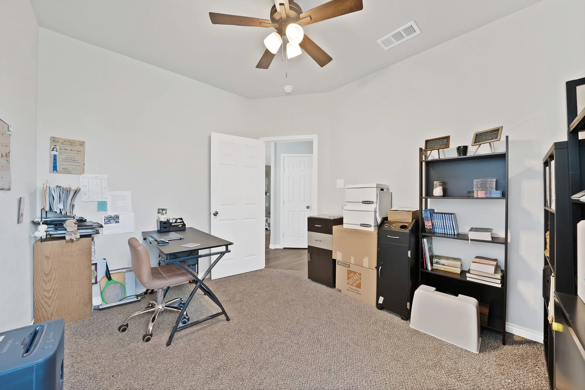 Carpeted room with a ceiling fan, light gray walls, and a paneled door
