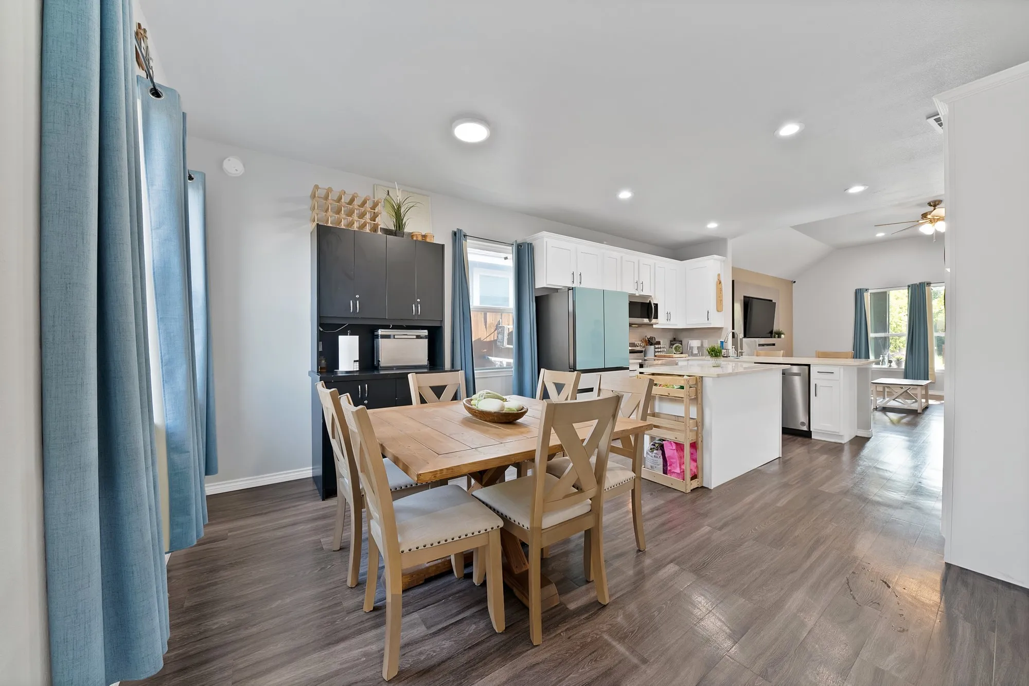 Wood-finish flooring throughout, white cabinetry, integrated island, and vaulted ceiling