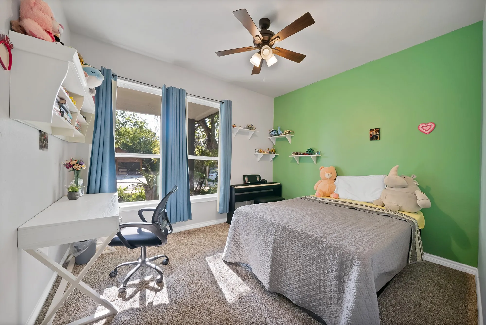 Carpeted room featuring a ceiling fan, a built-in floating desk, and multiple windows