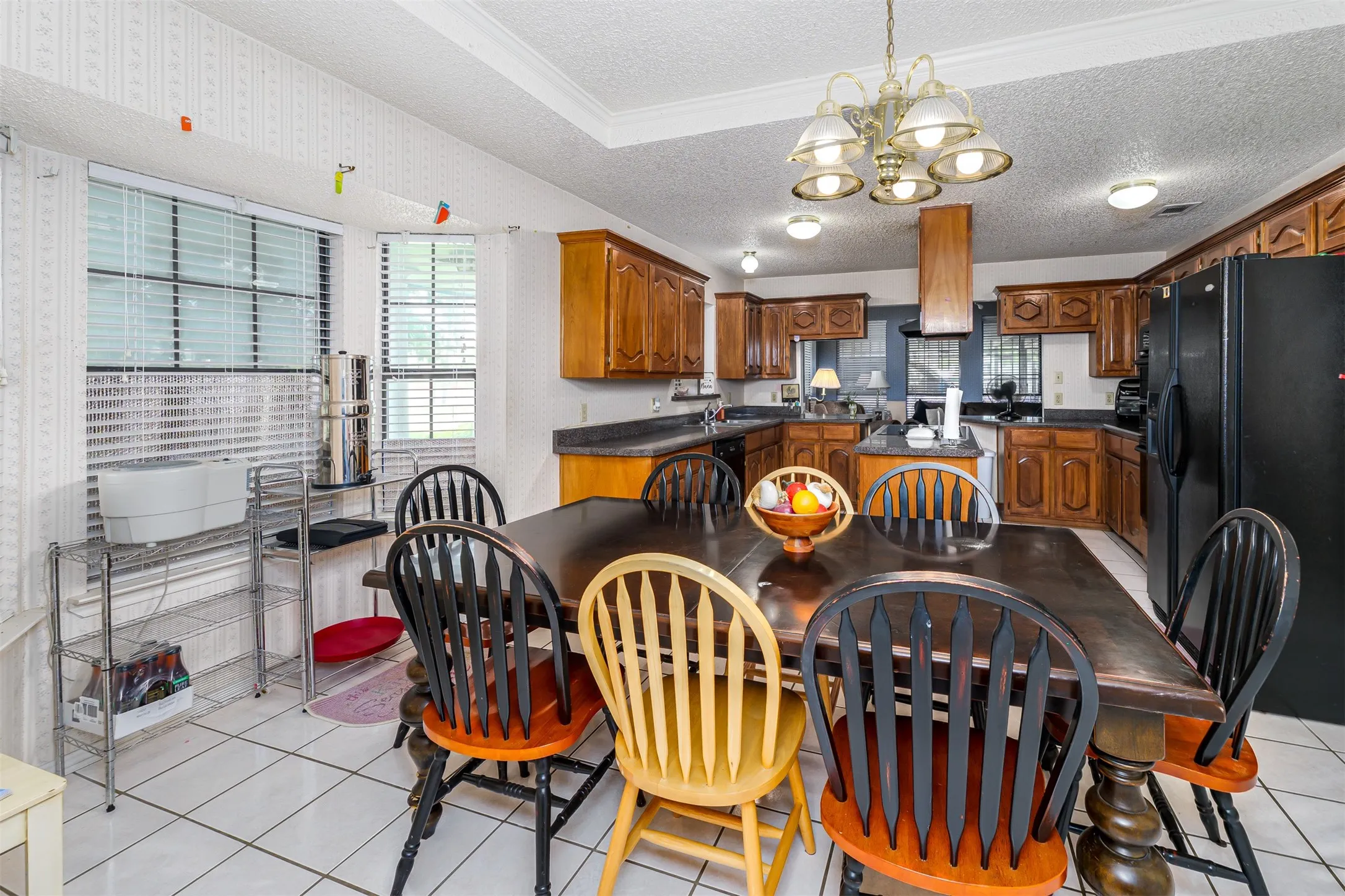 Kitchen featuring extensive wood cabinetry, black appliances, a central island, recessed lighting, and a decorative chandelier