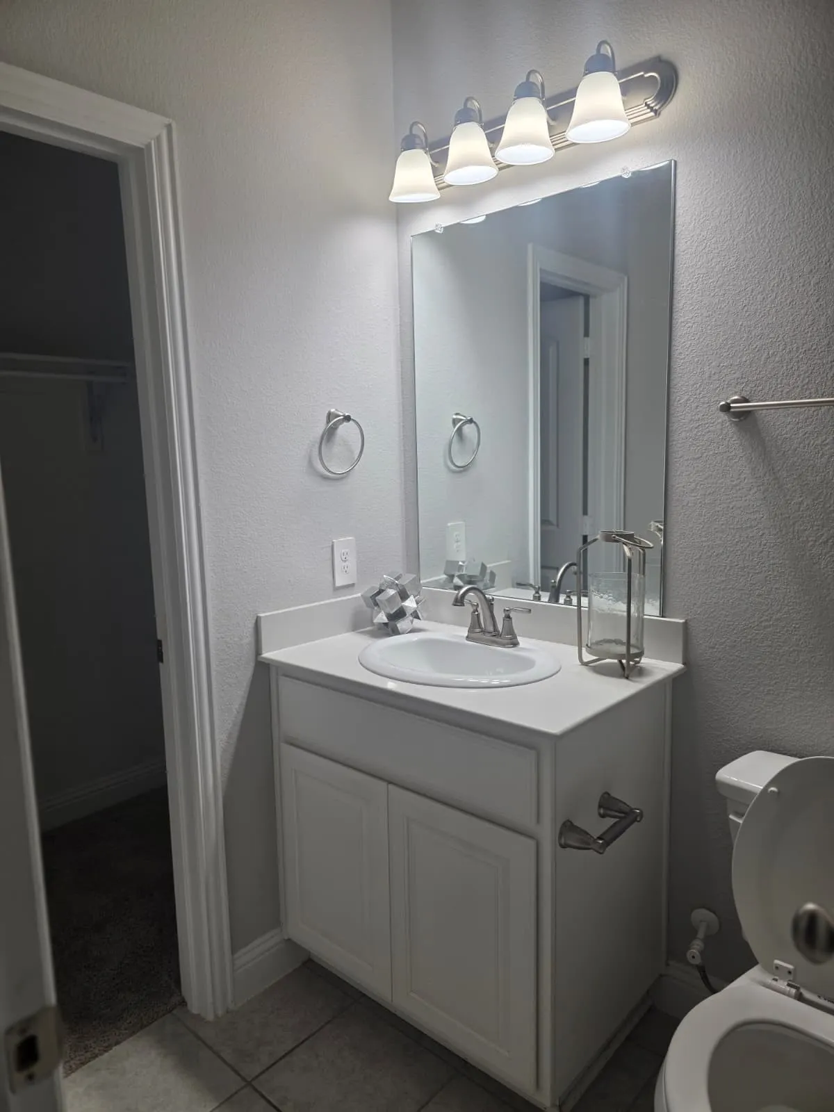 White vanity with integrated sink, brushed nickel faucet, large wall mirror, and overhead lighting fixture