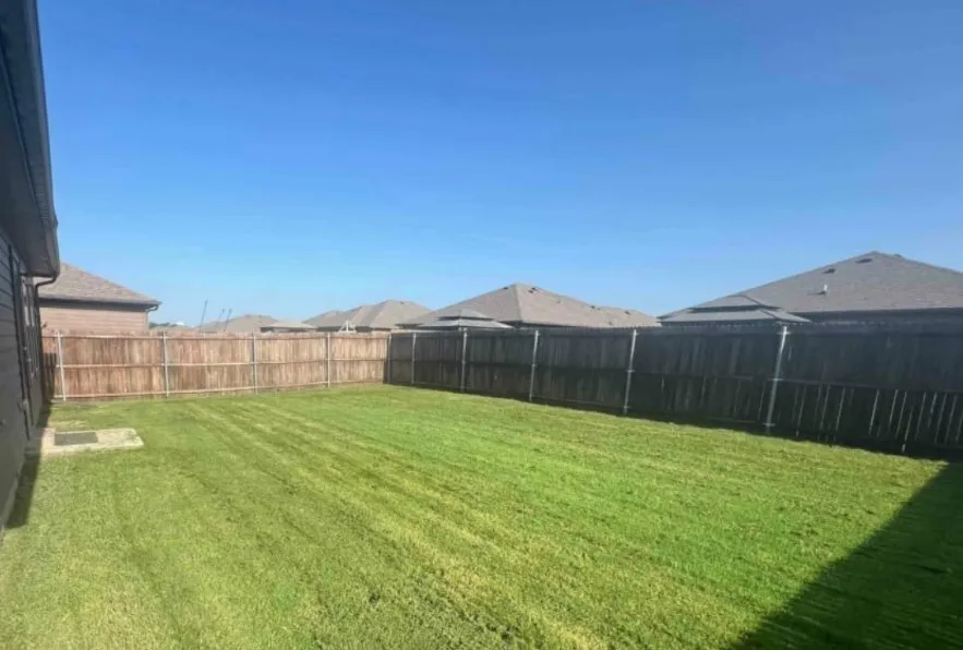 Expansive backyard featuring a manicured lawn and wood privacy fencing