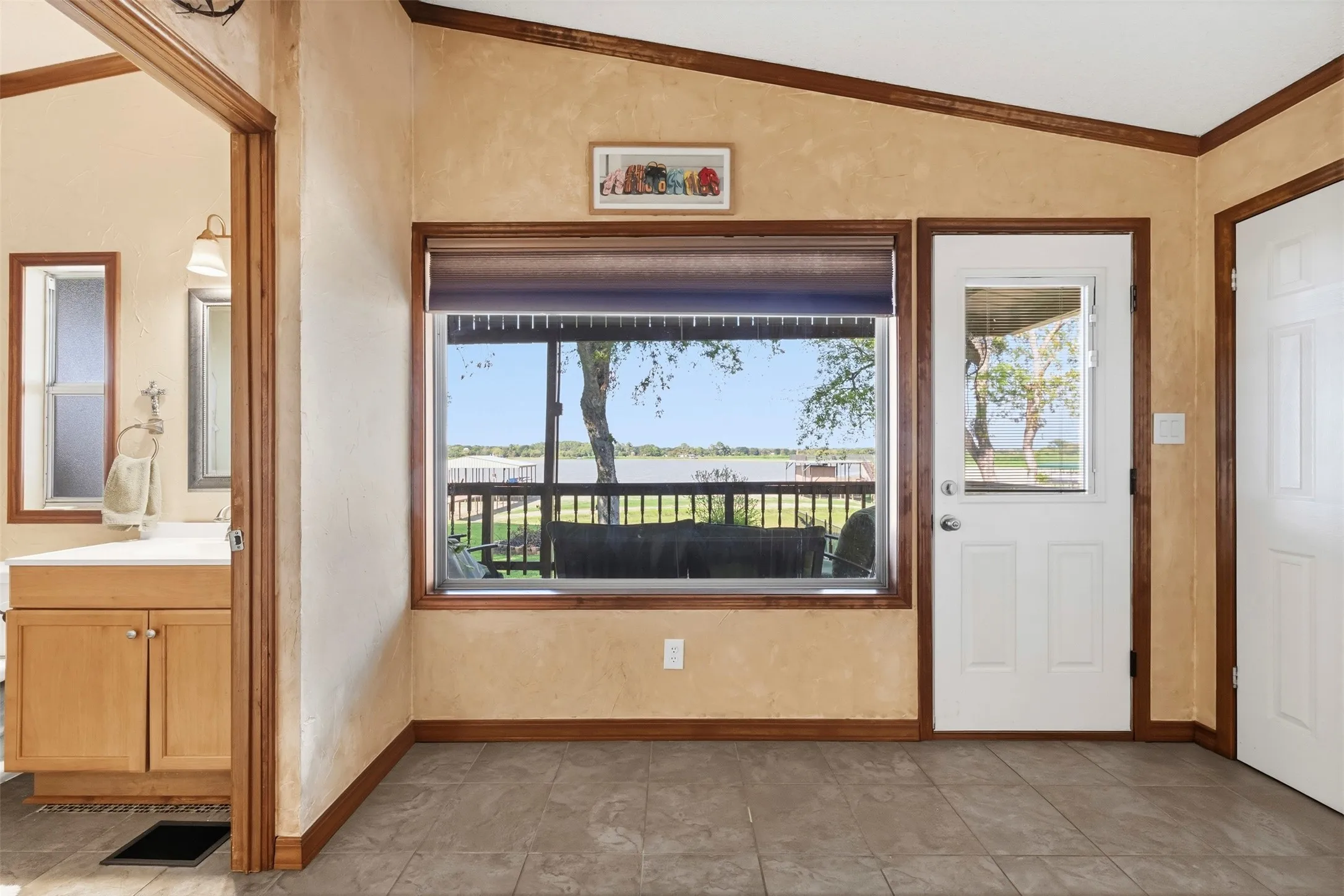 Tiled flooring, wood-finish trim, built-in vanity with cabinetry, and an exterior door with a window panel