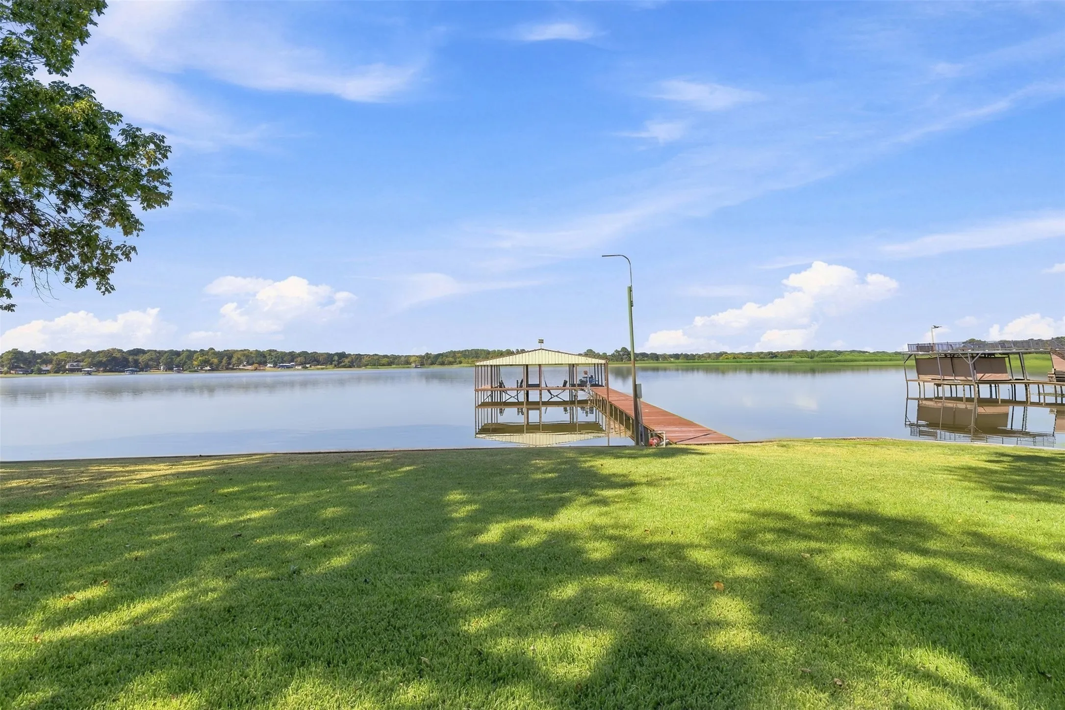 Expansive waterfront property featuring a covered boat dock, extended wooden pier, and an additional open dock structure