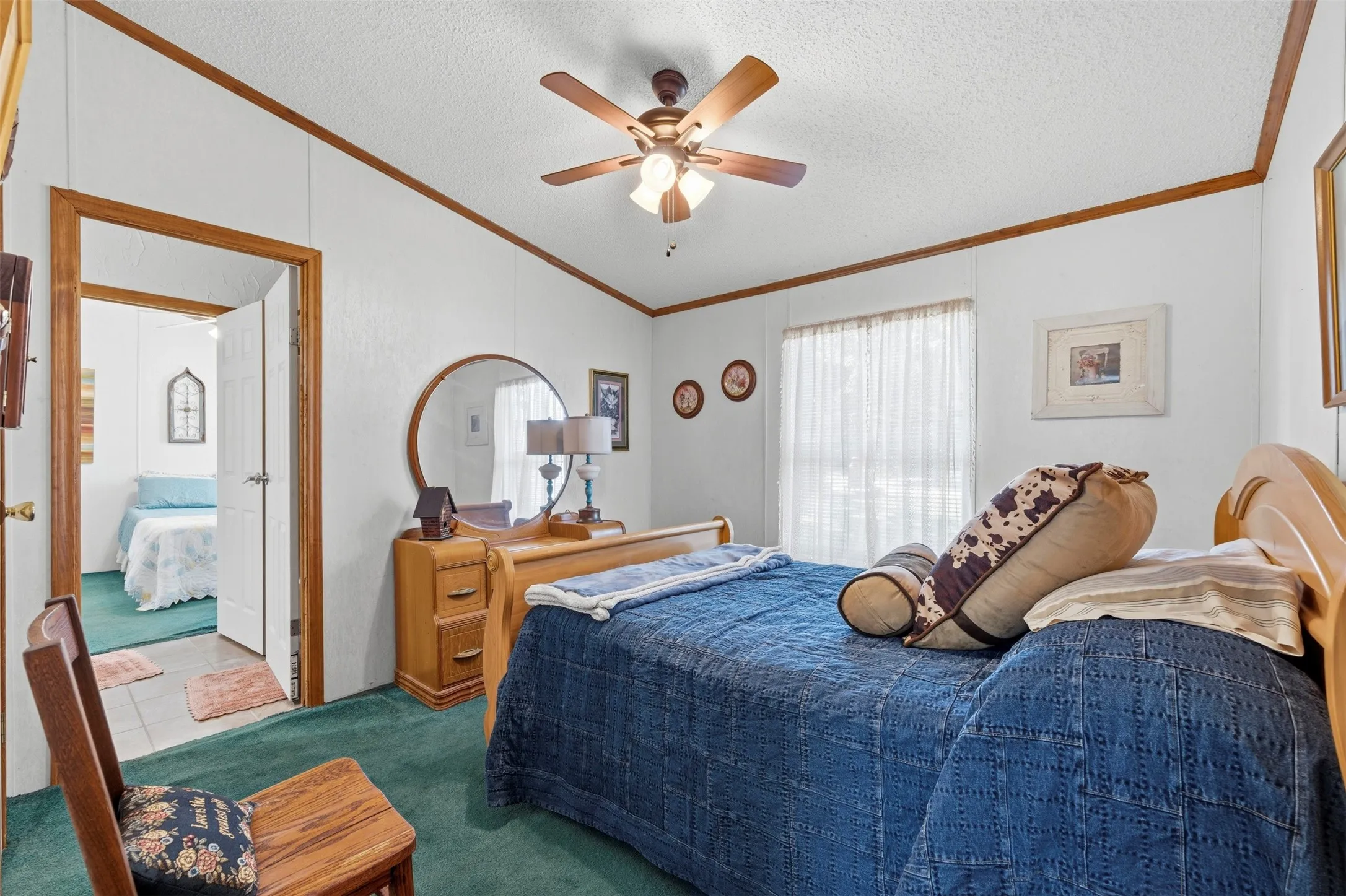 Spacious bedroom featuring wood-finish trim, a ceiling fan with integrated lighting, and a large window with privacy coverings