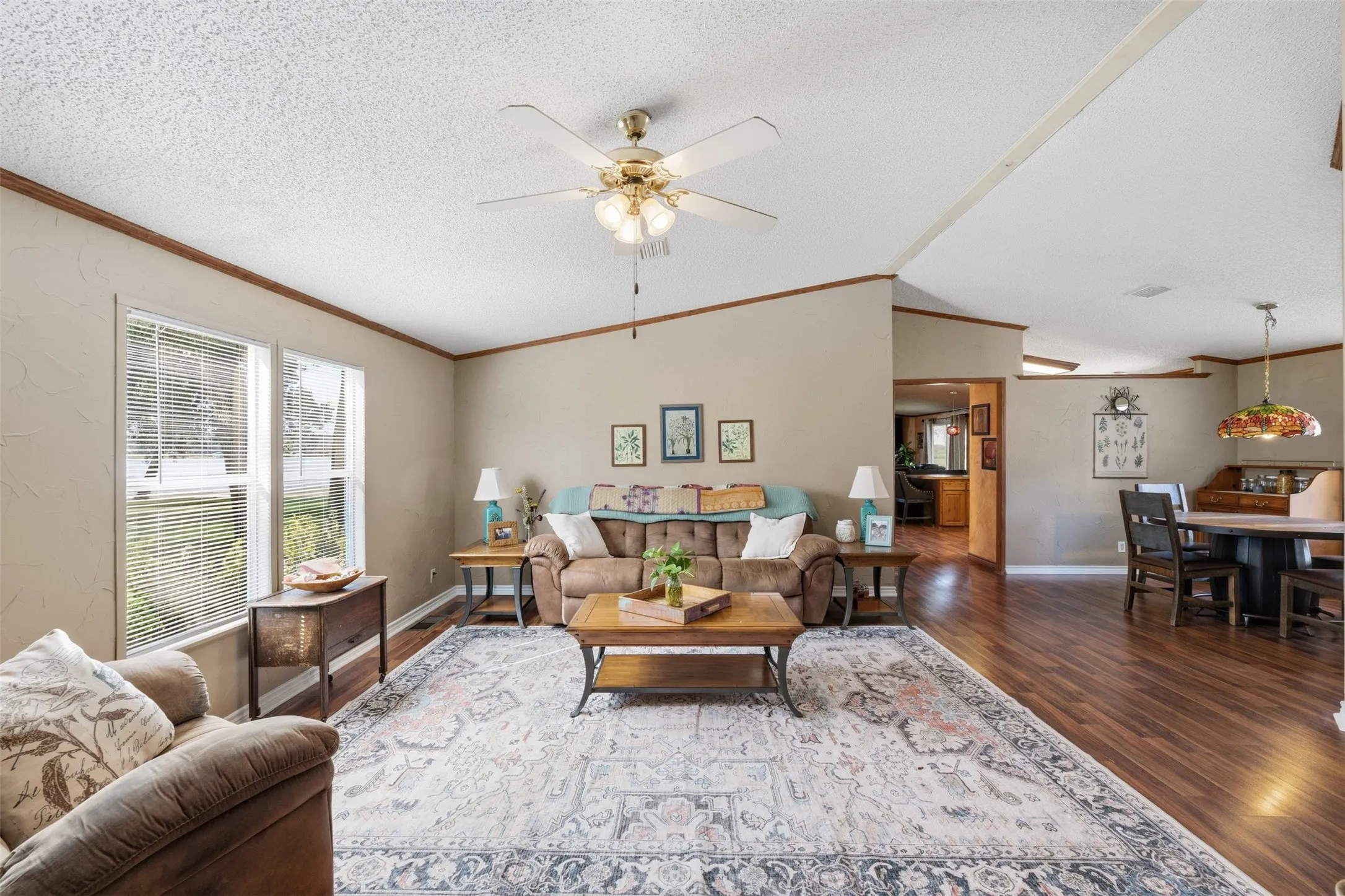 Spacious living area featuring wood-finish flooring, two large windows, and a ceiling fan