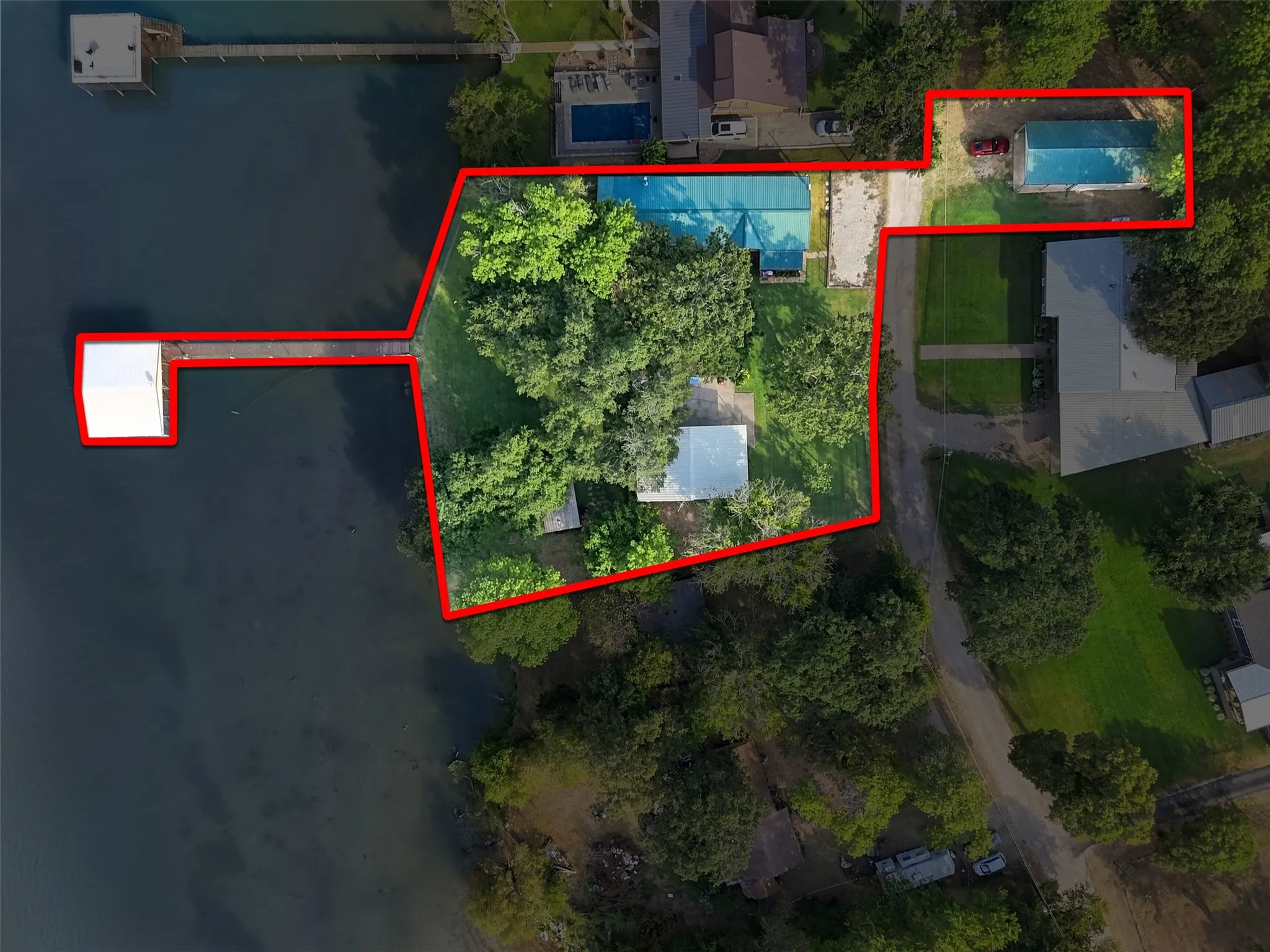 Waterfront property with extensive boat dock, covered boat slip, mature trees, and a separate detached building