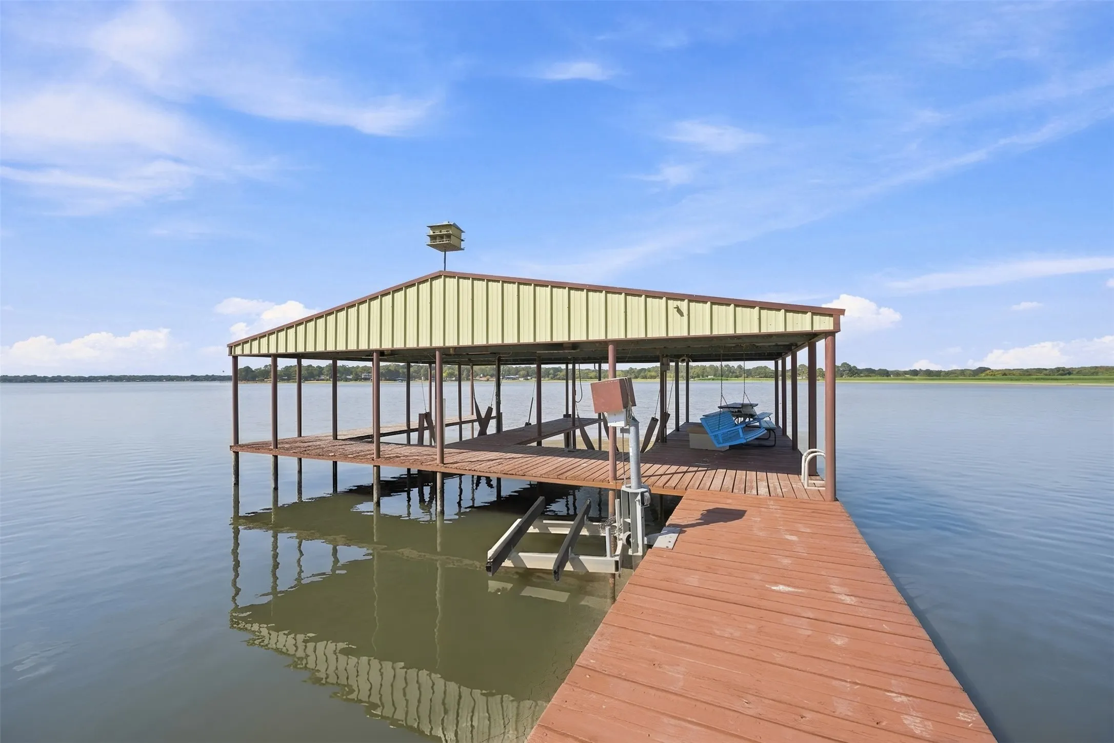 Wood-finish boat dock with a covered slip, metal roof, and integrated boat lift