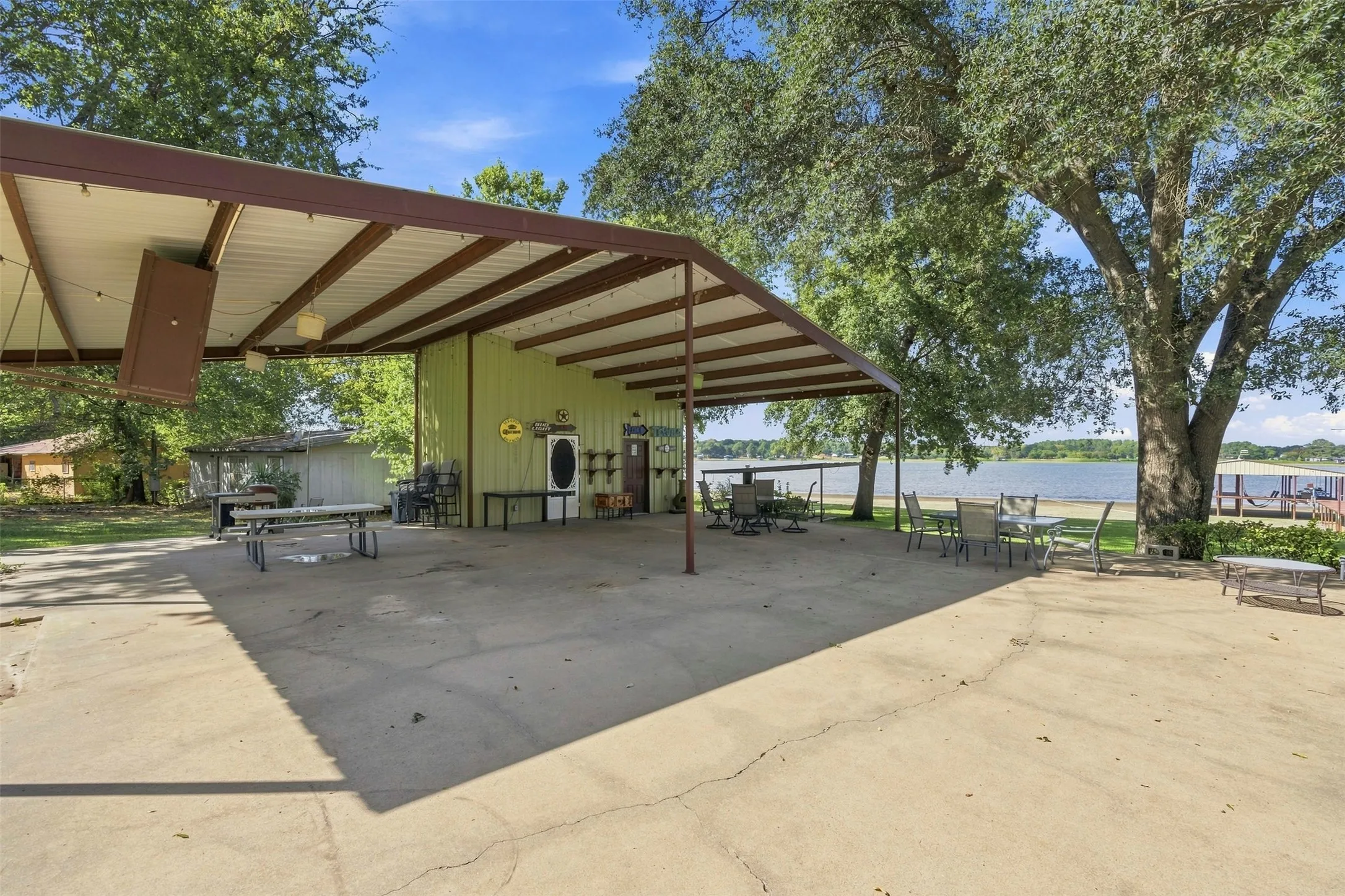 Expansive covered pavillion with concrete flooring, supported by a metal frame, offering direct waterfront access