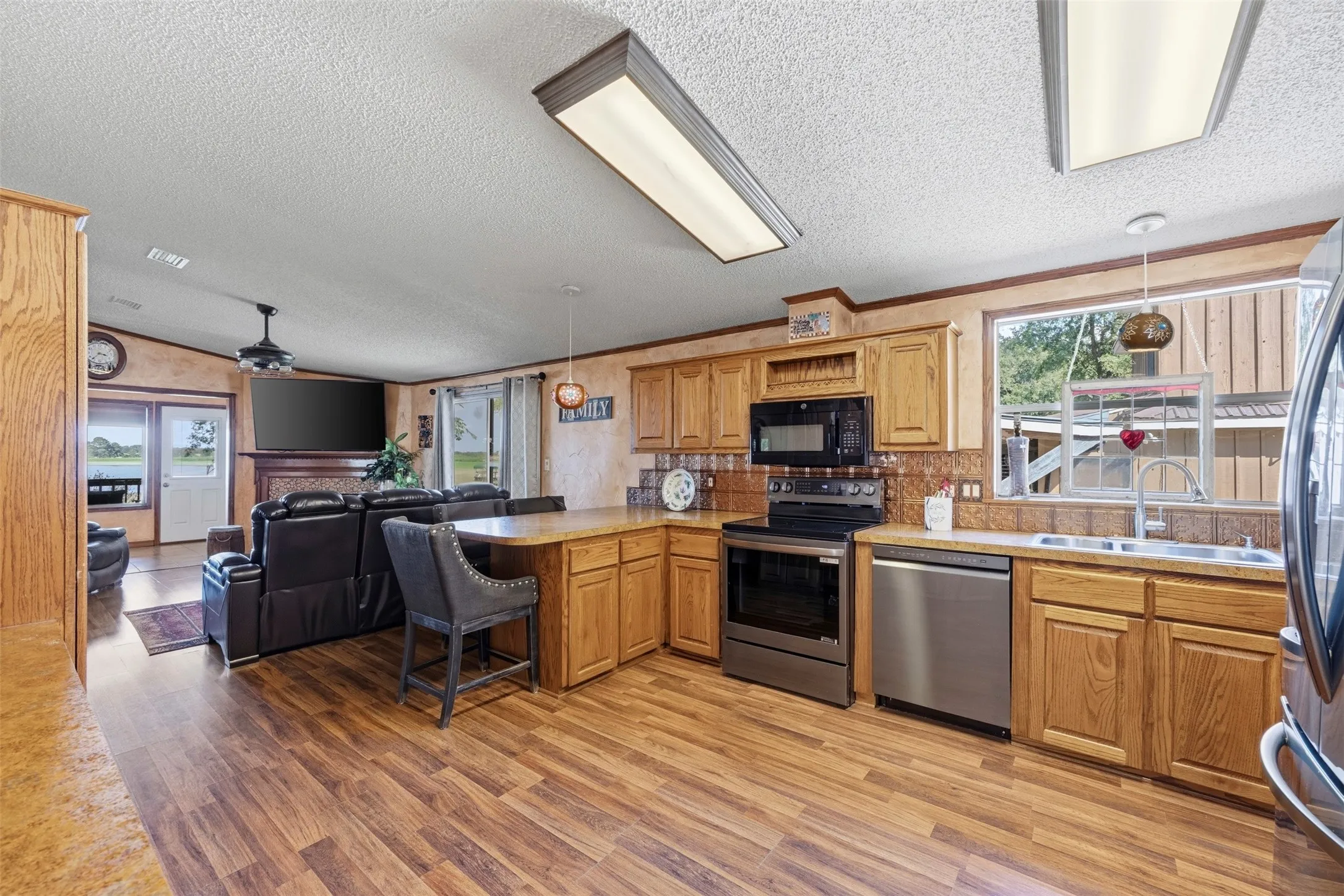 Open-concept kitchen featuring wood-finish flooring, stainless steel appliances, and wood cabinetry